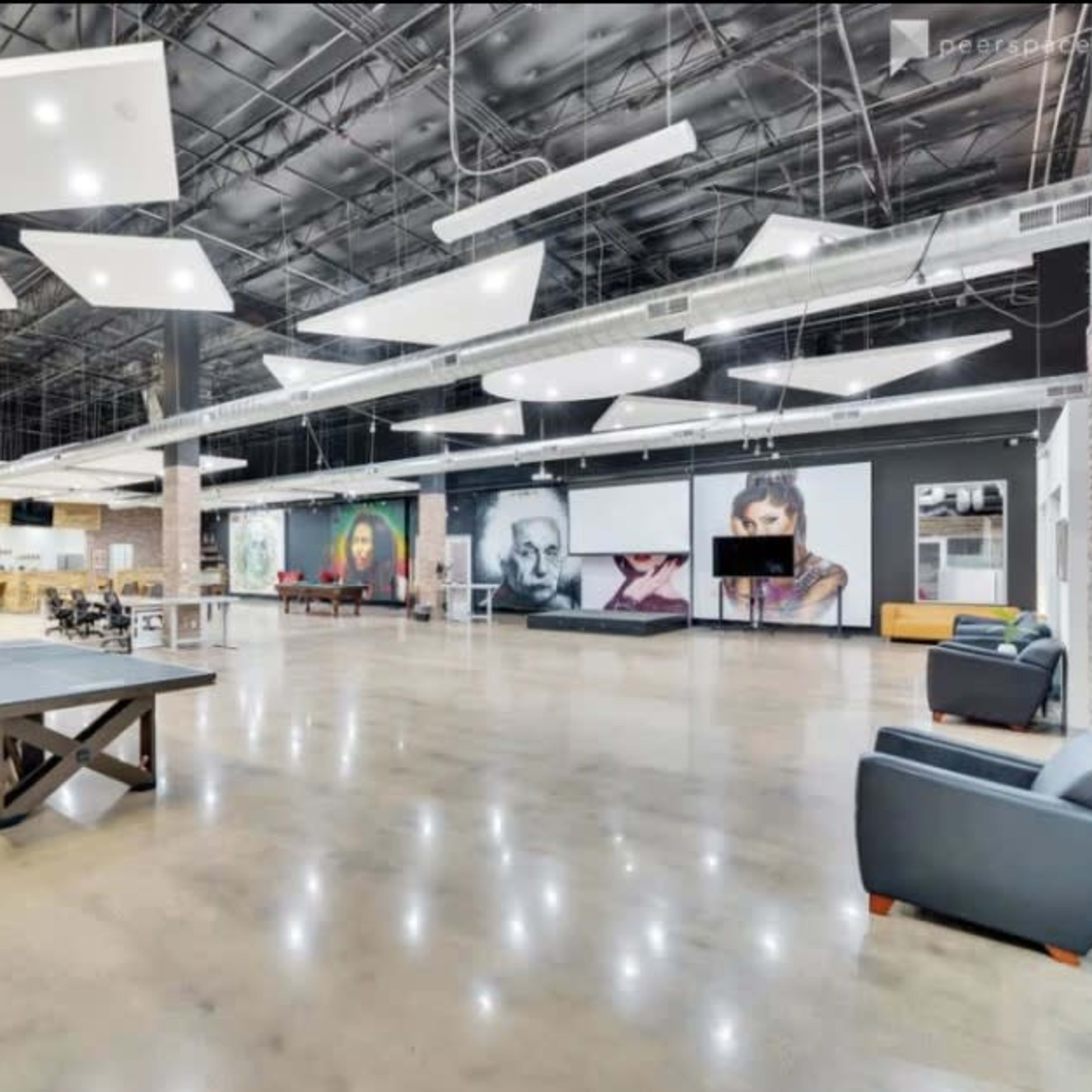 A large, modern open space with polished concrete floors, a billiards table, and various wall-mounted artworks.