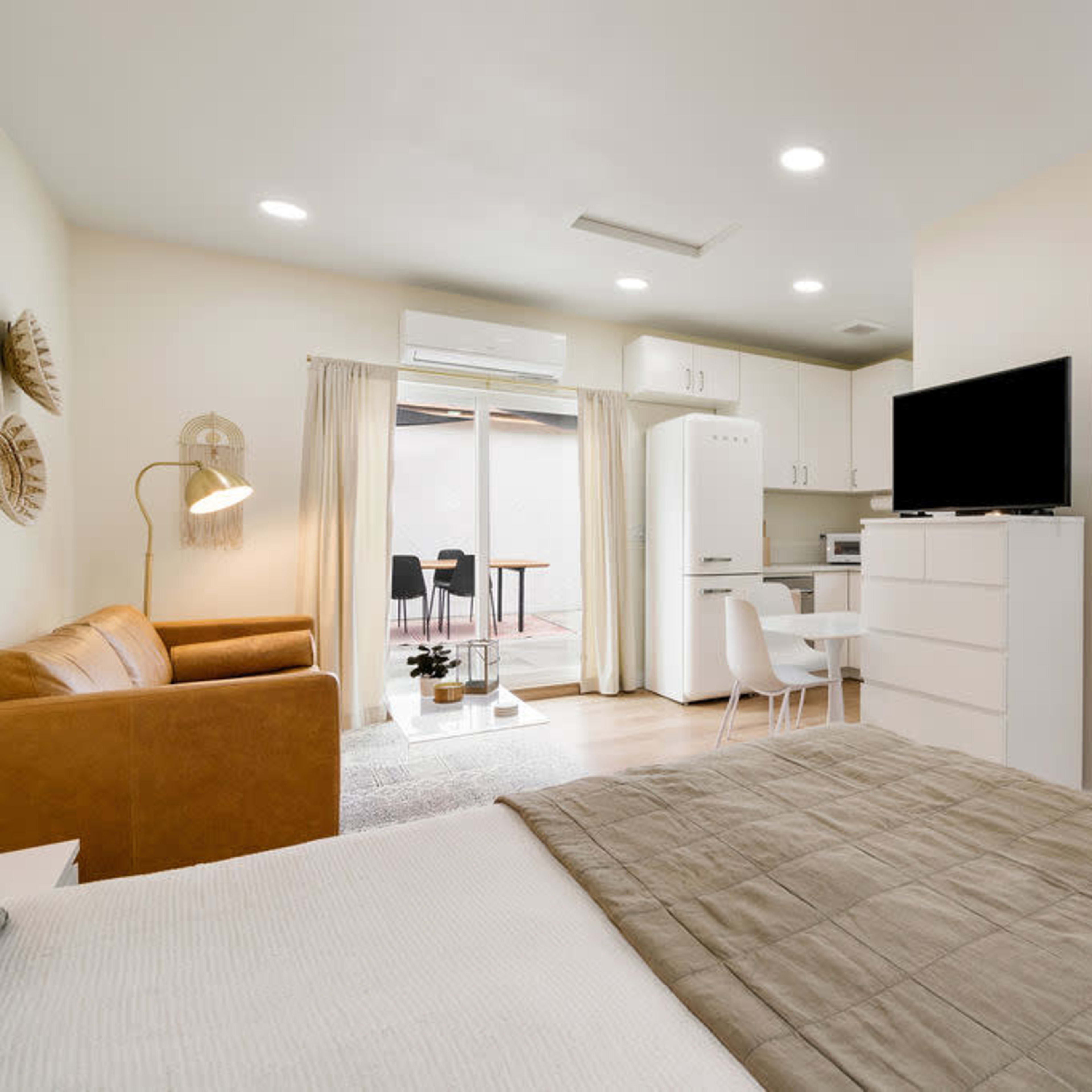 A compact living space features a bed, a seating area, a kitchen, and a bathroom with laundry facilities.