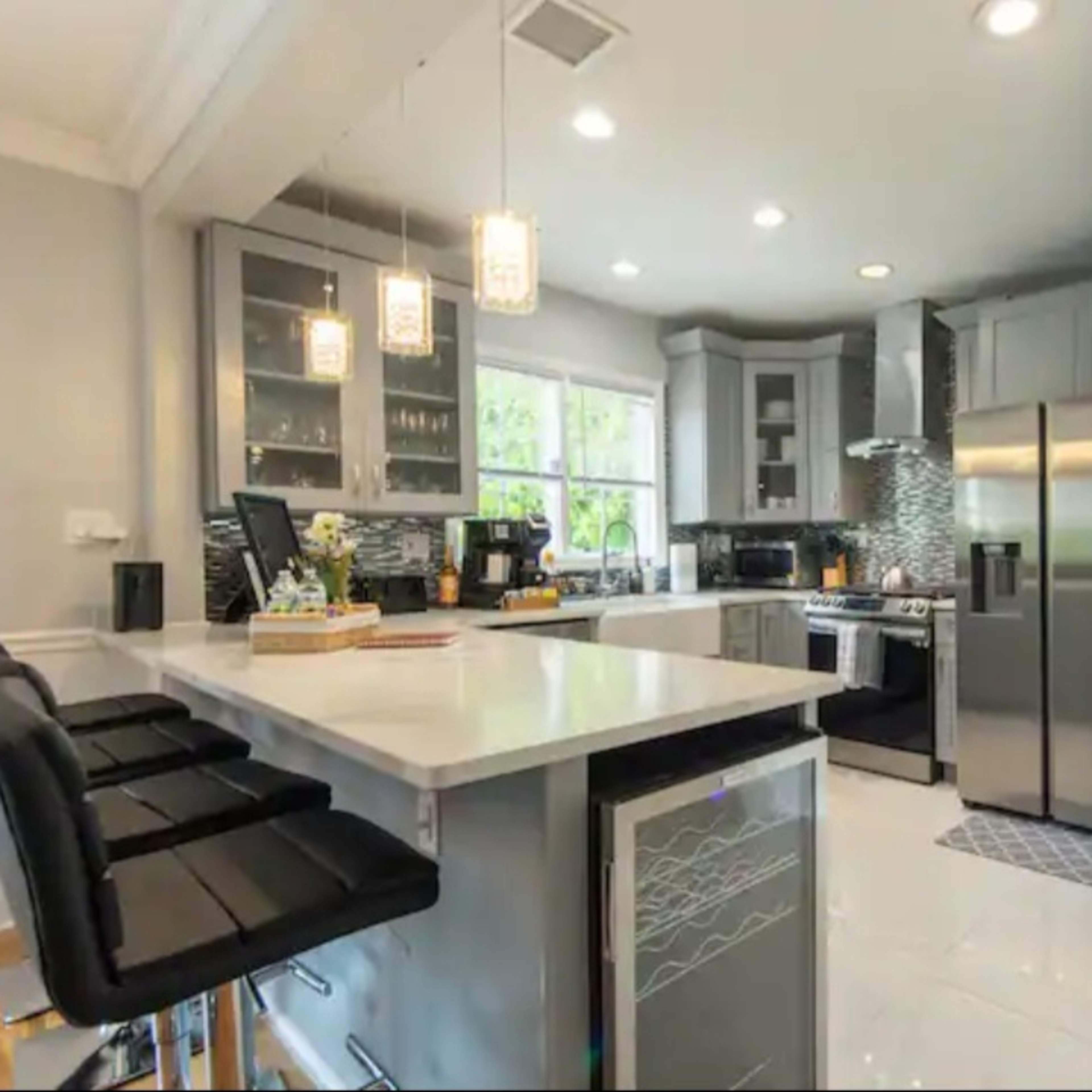 A modern kitchen featuring gray cabinetry, stainless steel appliances, and a central island with bar stools.