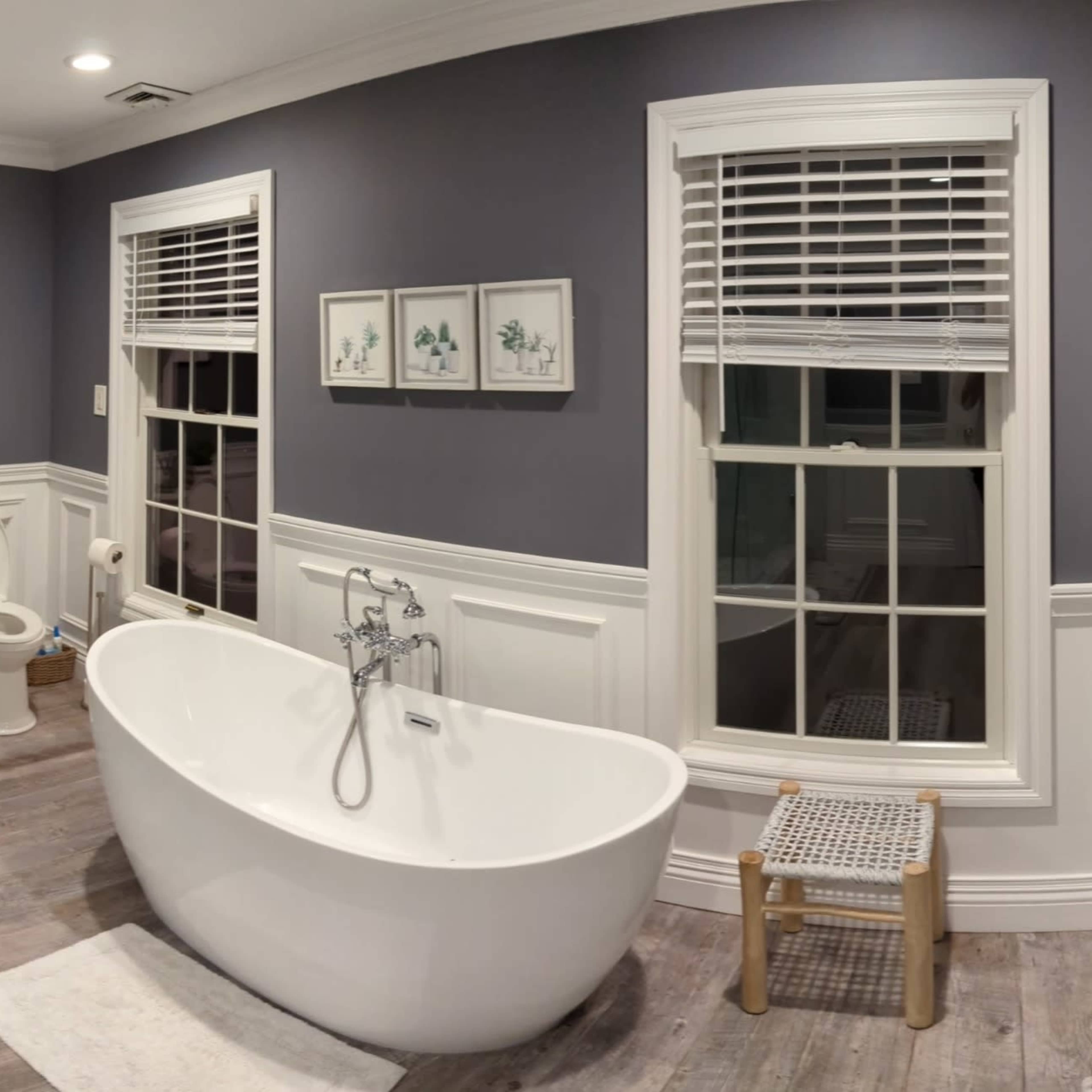 A modern bathroom featuring a glass shower enclosure, a freestanding bathtub, dual sinks with a large mirror, and light-colored wooden flooring.