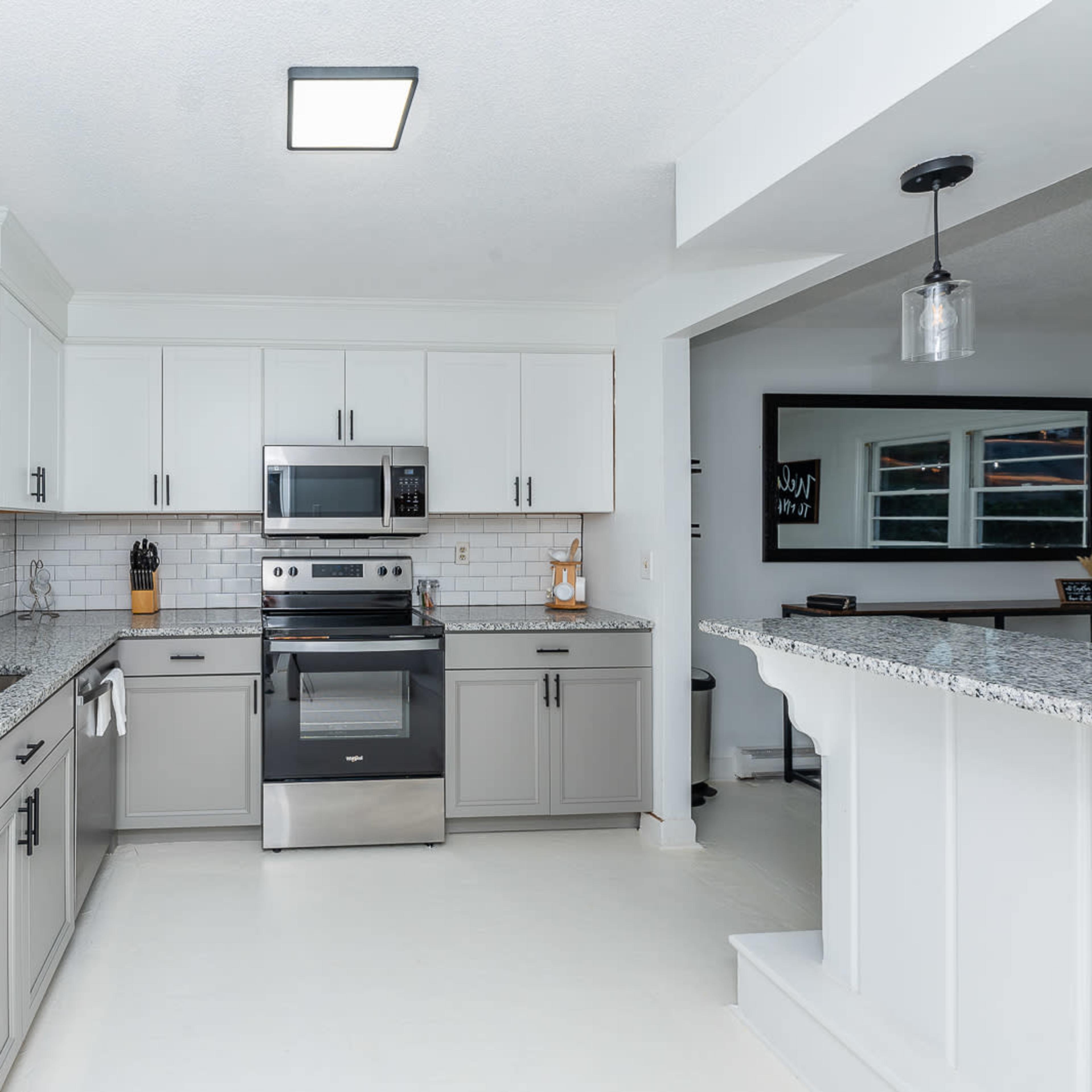 A modern kitchen with gray cabinetry, stainless steel appliances, and a granite countertop.