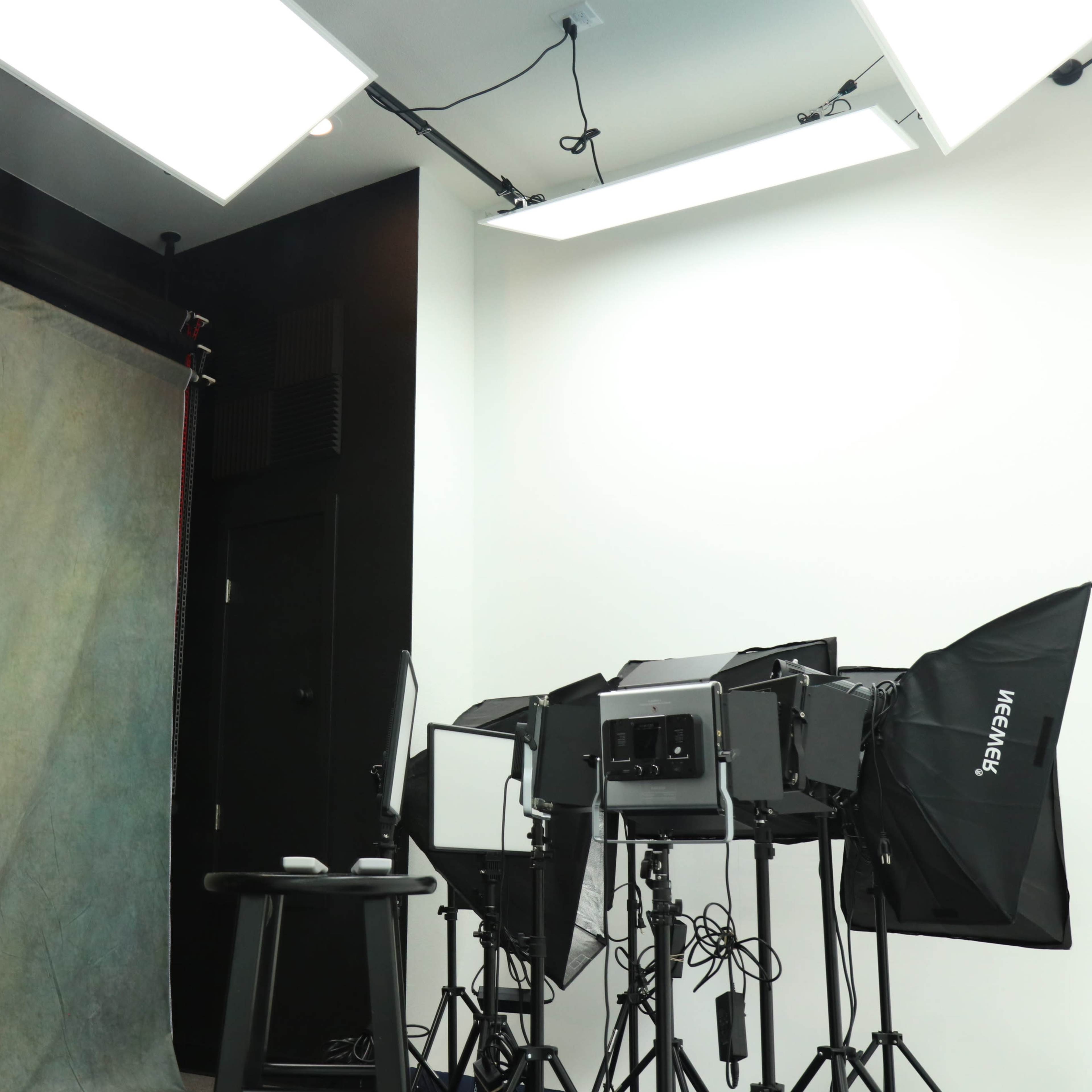 A photography studio with softboxes, a backdrop, and a stool.