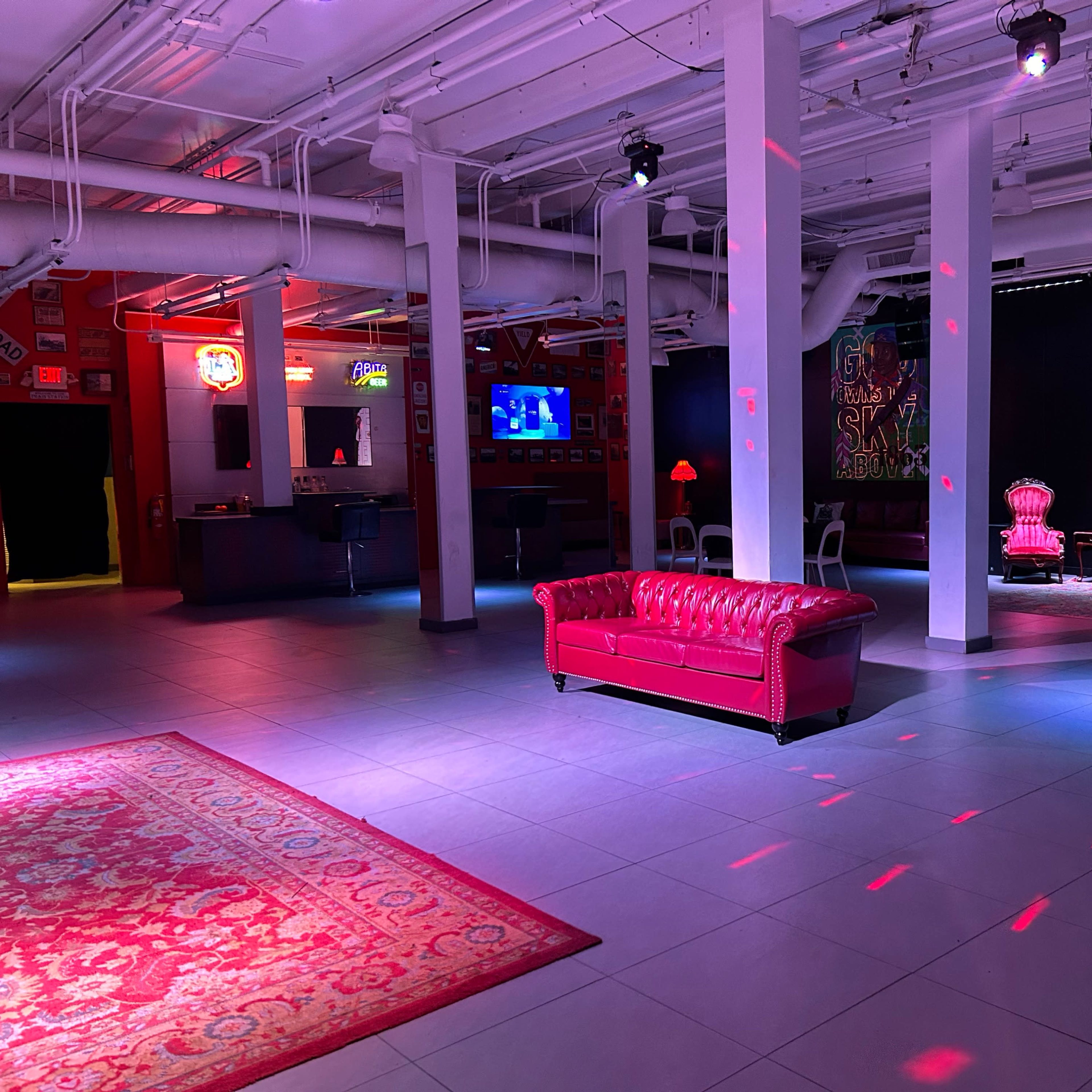 An interior space featuring a red leather couch, decorative lighting effects, and a patterned rug on the floor.