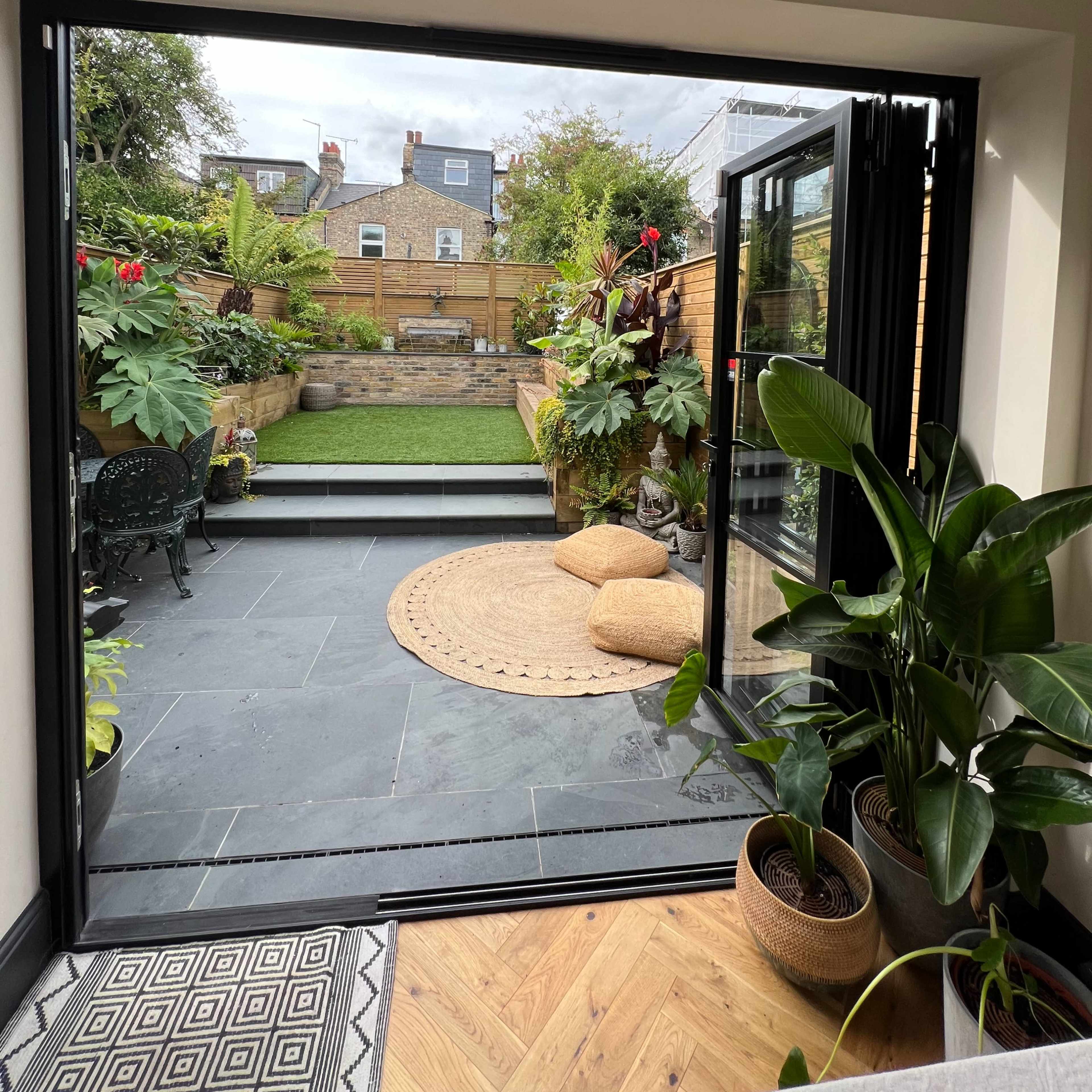 A modern interior opens to a landscaped garden with greenery and decorative elements.