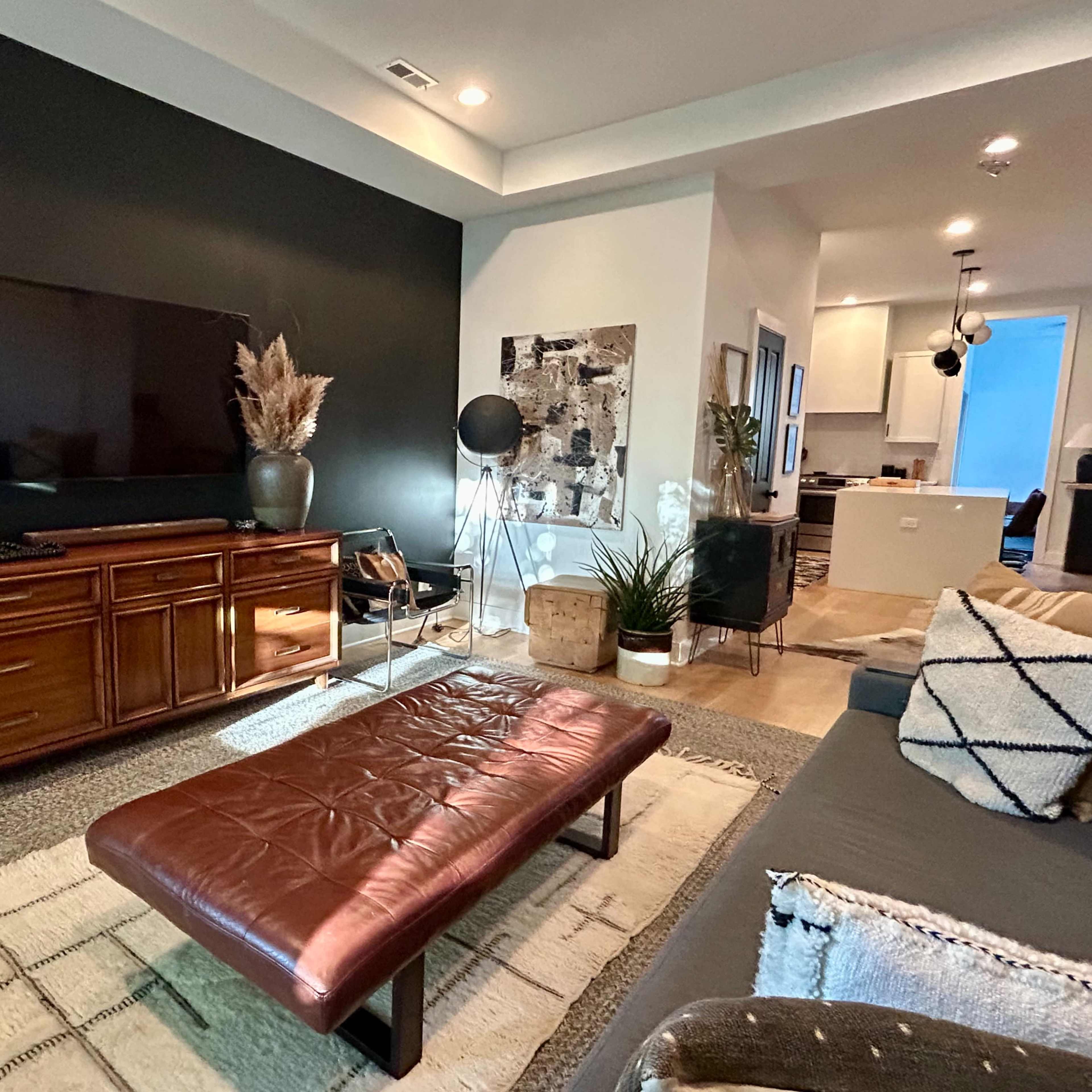 A modern living room with a dark accent wall, a brown leather coffee table, and an entertainment unit against the wall.