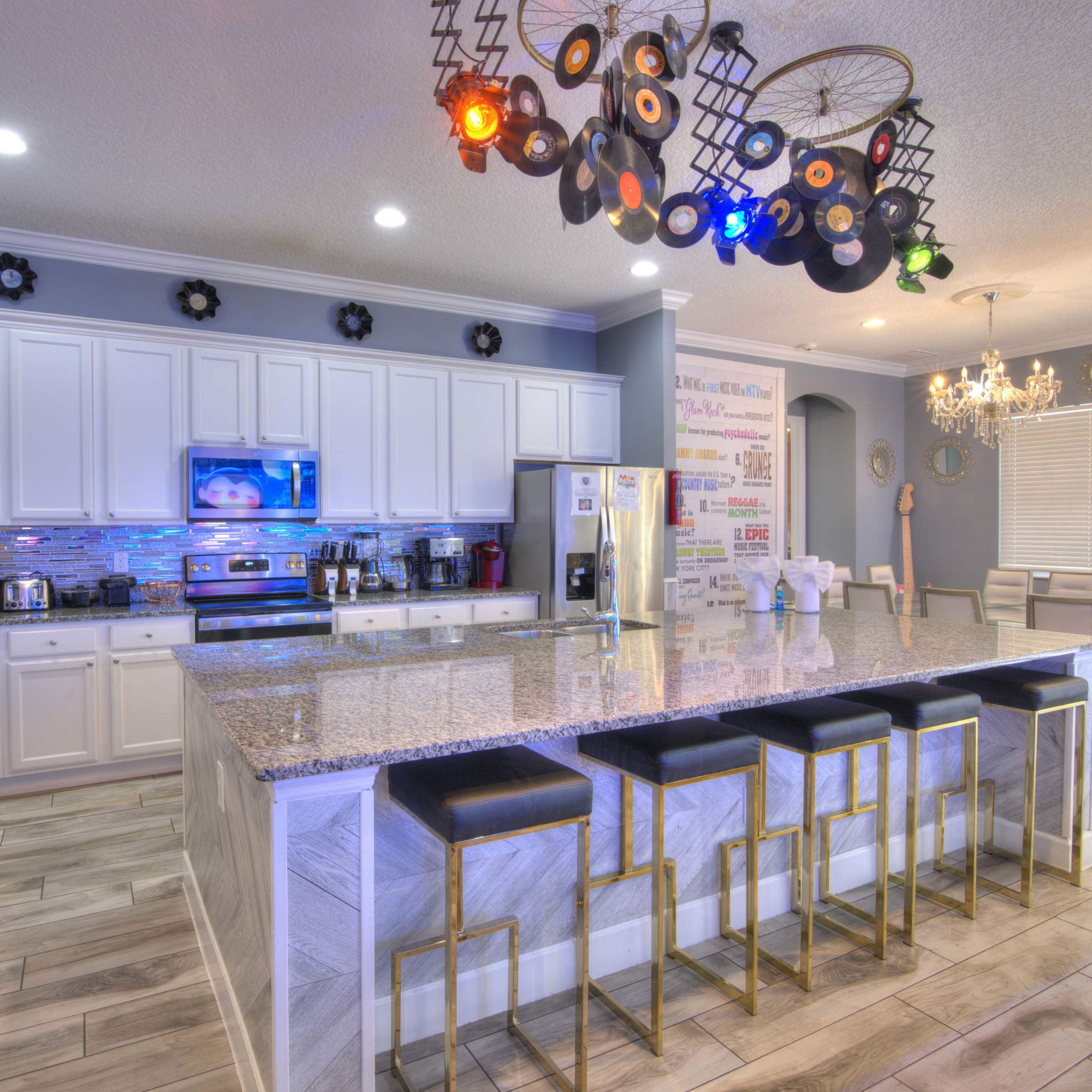 The kitchen features a large island with bar seating, stainless steel appliances, and modern cabinetry.