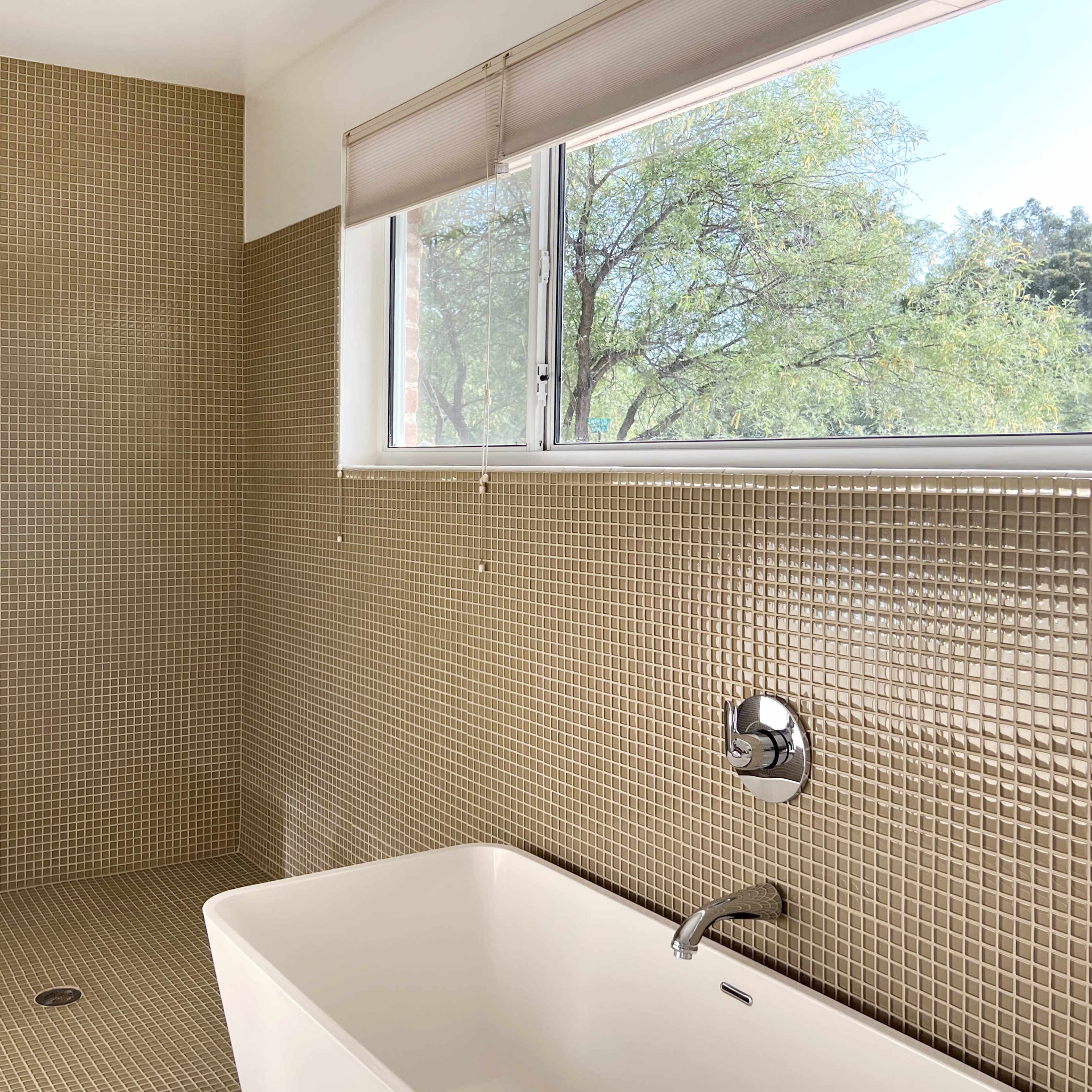 A modern bathroom features a walk-in shower with tiled walls and a freestanding bathtub under a window.