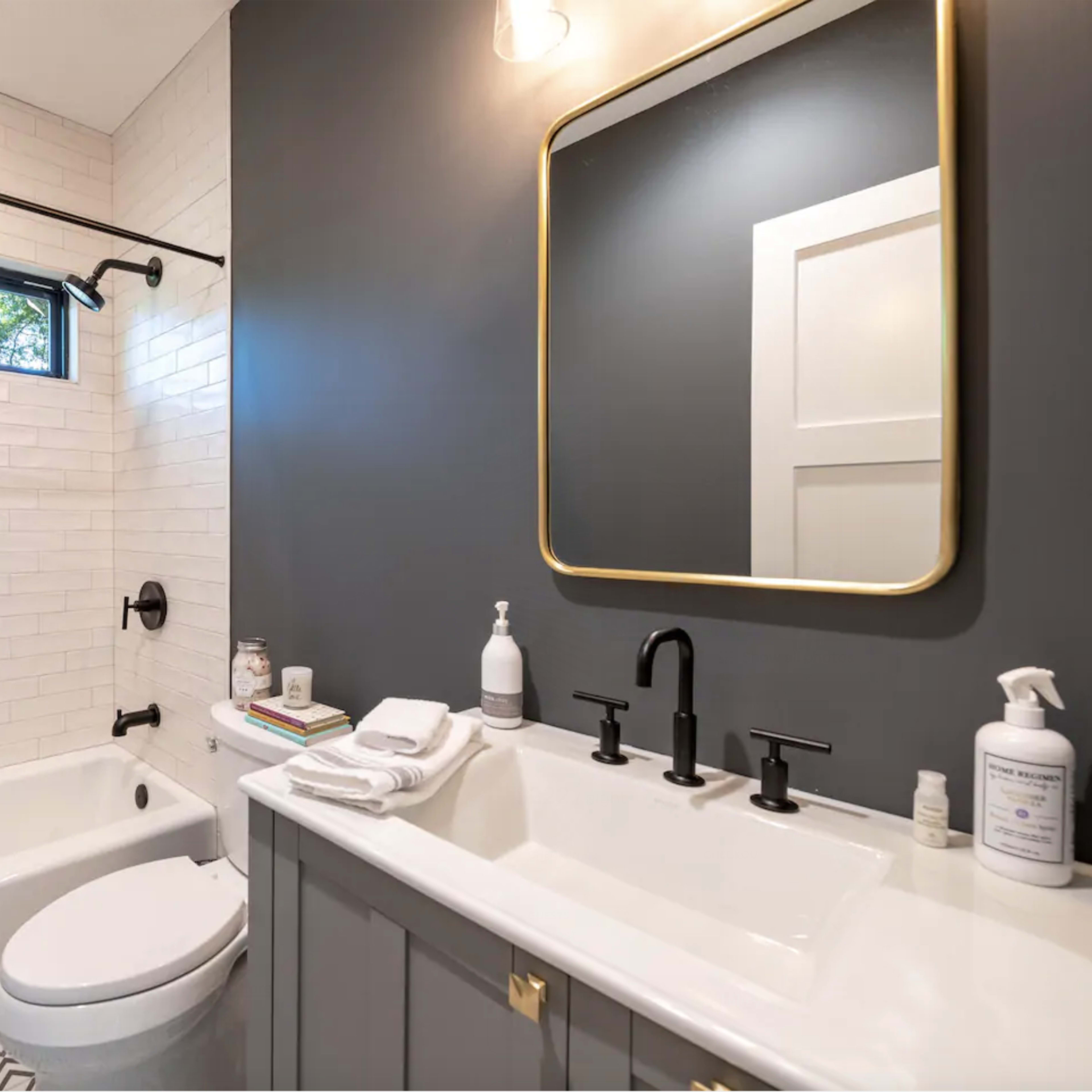 A modern bathroom featuring a white shower curtain, a sleek rectangular mirror, and a dual-sink vanity with black fixtures.