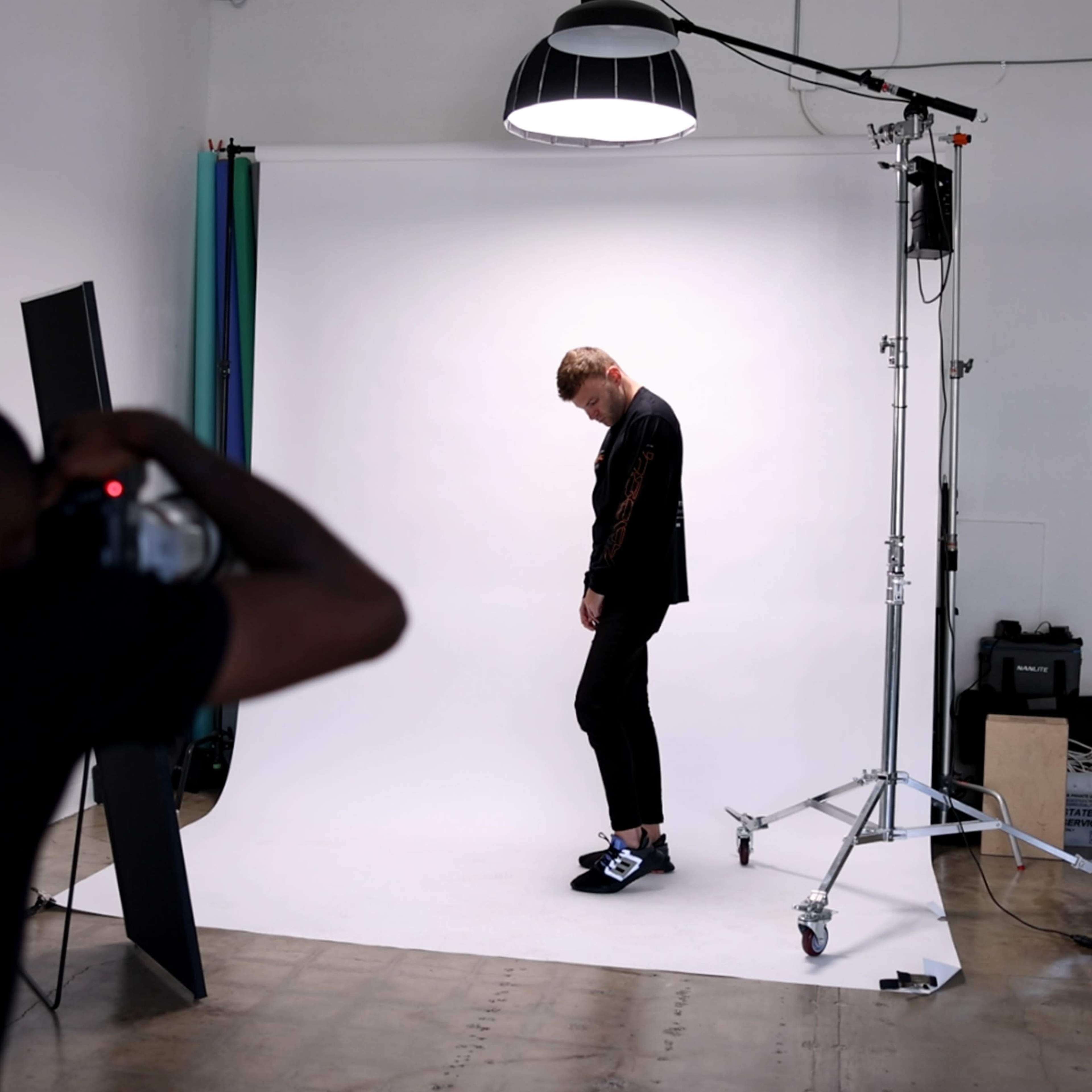 A photographer captures an individual posing against a white backdrop in a studio setting.