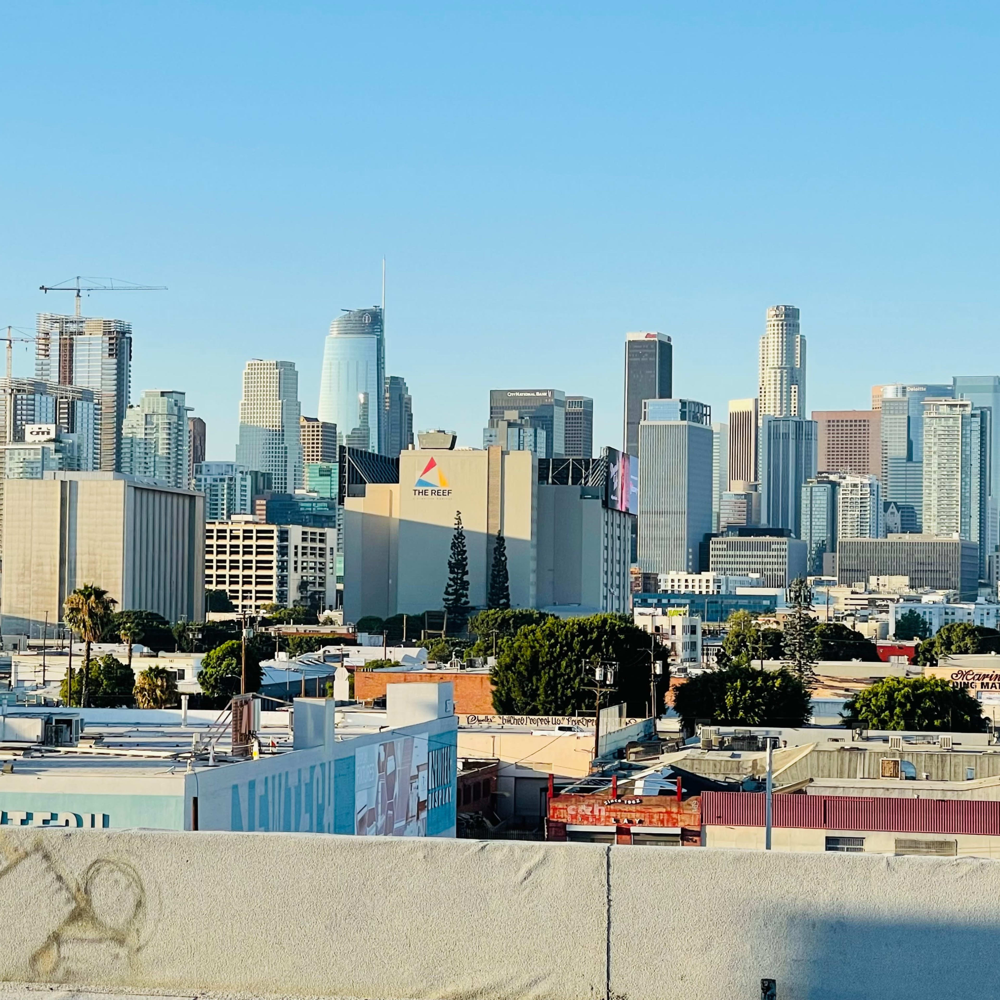 A view of the downtown Los Angeles skyline with various high-rise buildings and a clear blue sky.