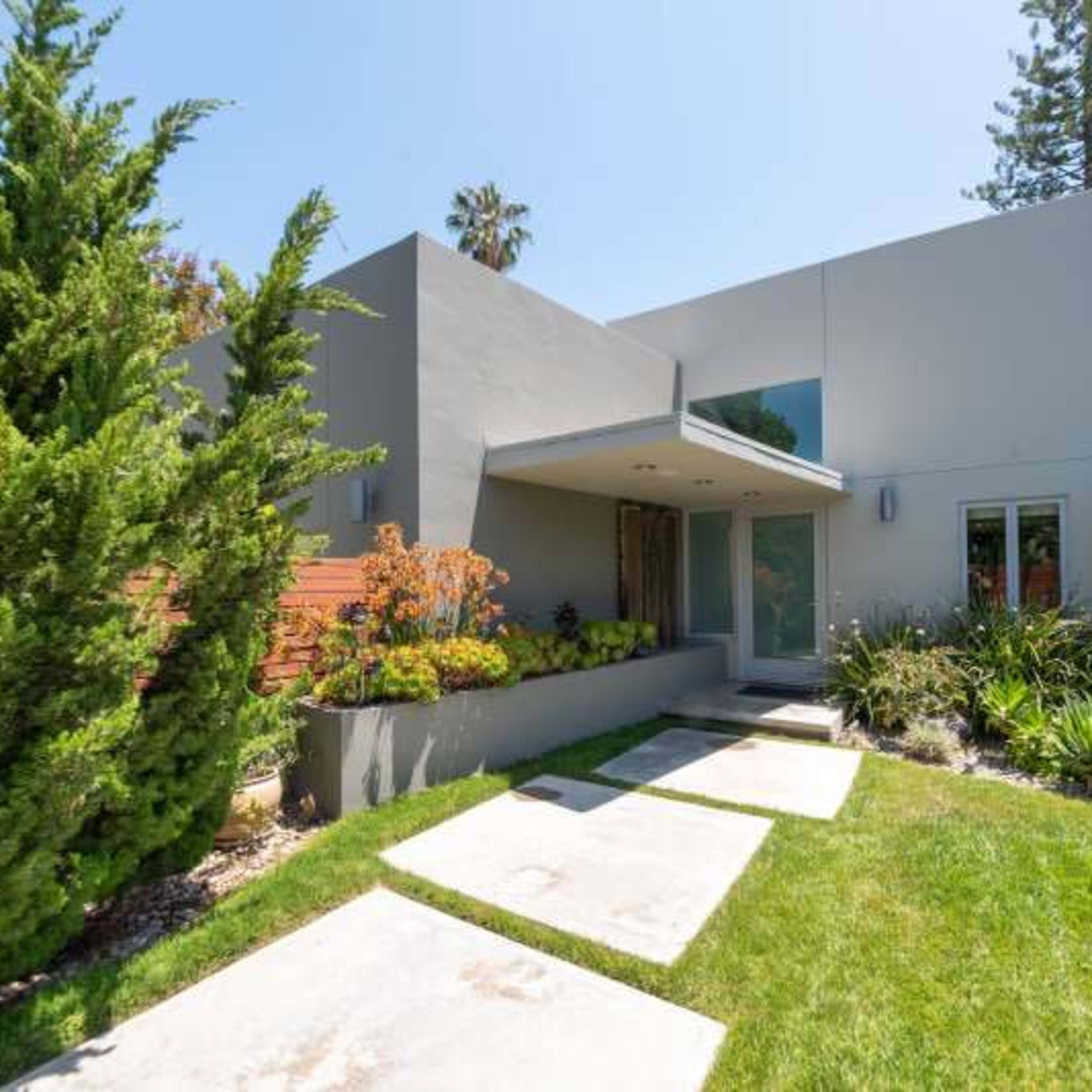 A modern gray house with a landscaped front yard, featuring a pathway leading to the entrance.