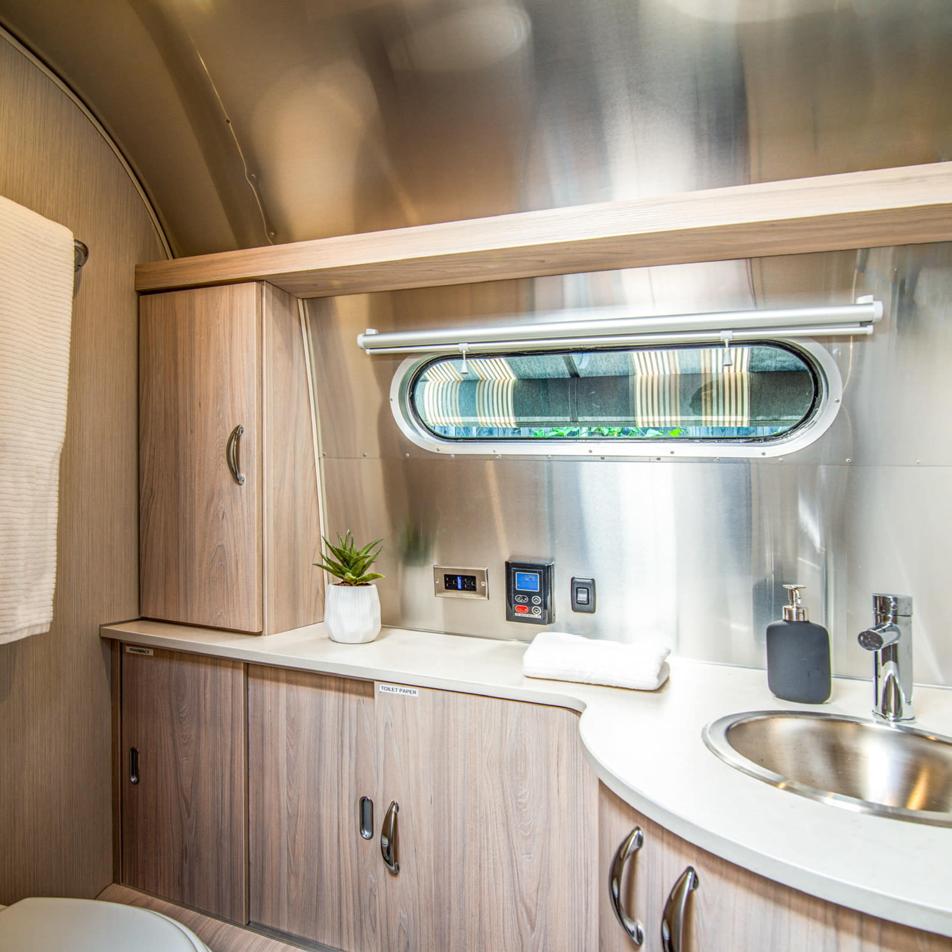A compact, modern bathroom with a toilet, sink, and wooden cabinetry, illuminated by overhead lighting.