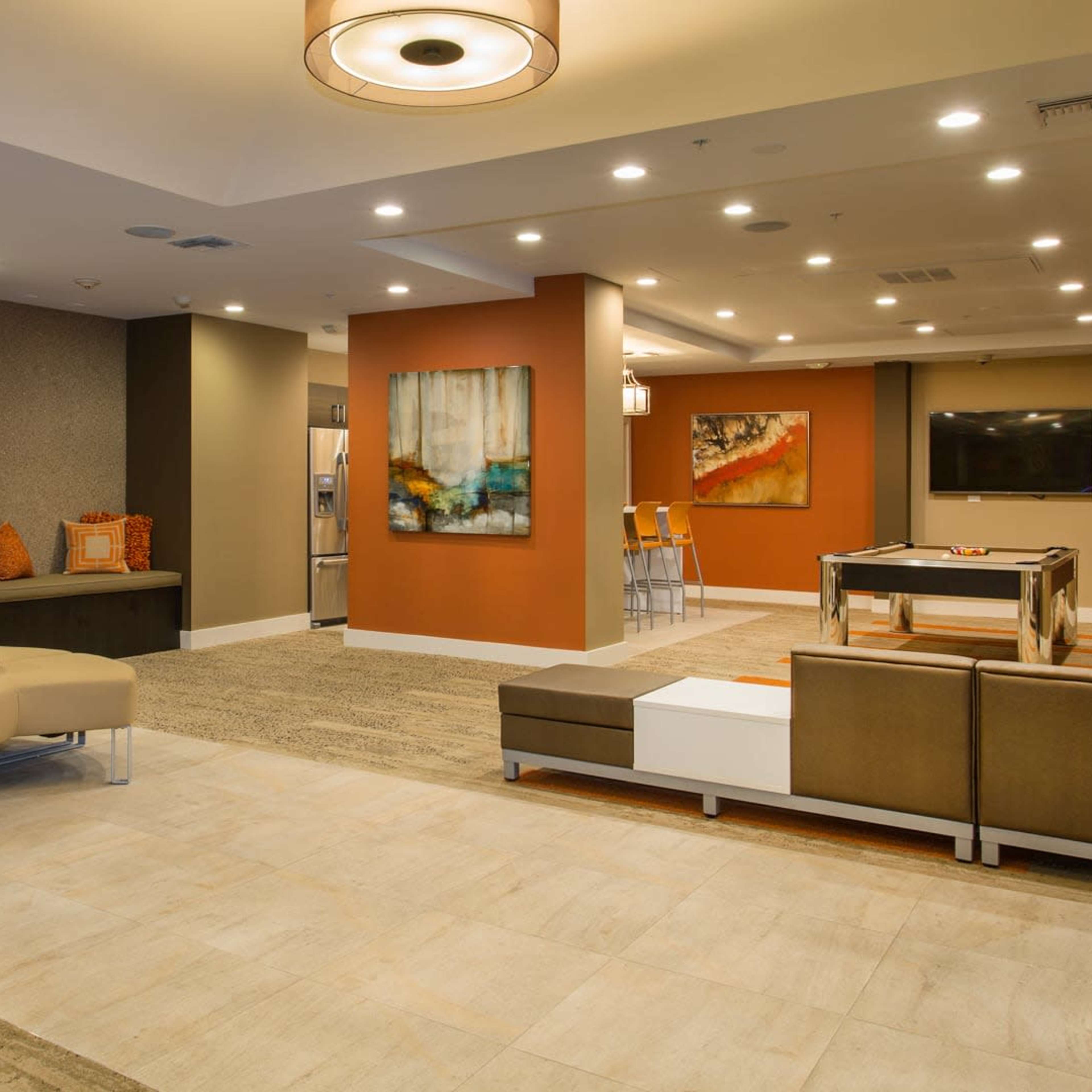 A modern lounge area with sofas, a round seating arrangement, an electric fireplace, and artwork on the walls.