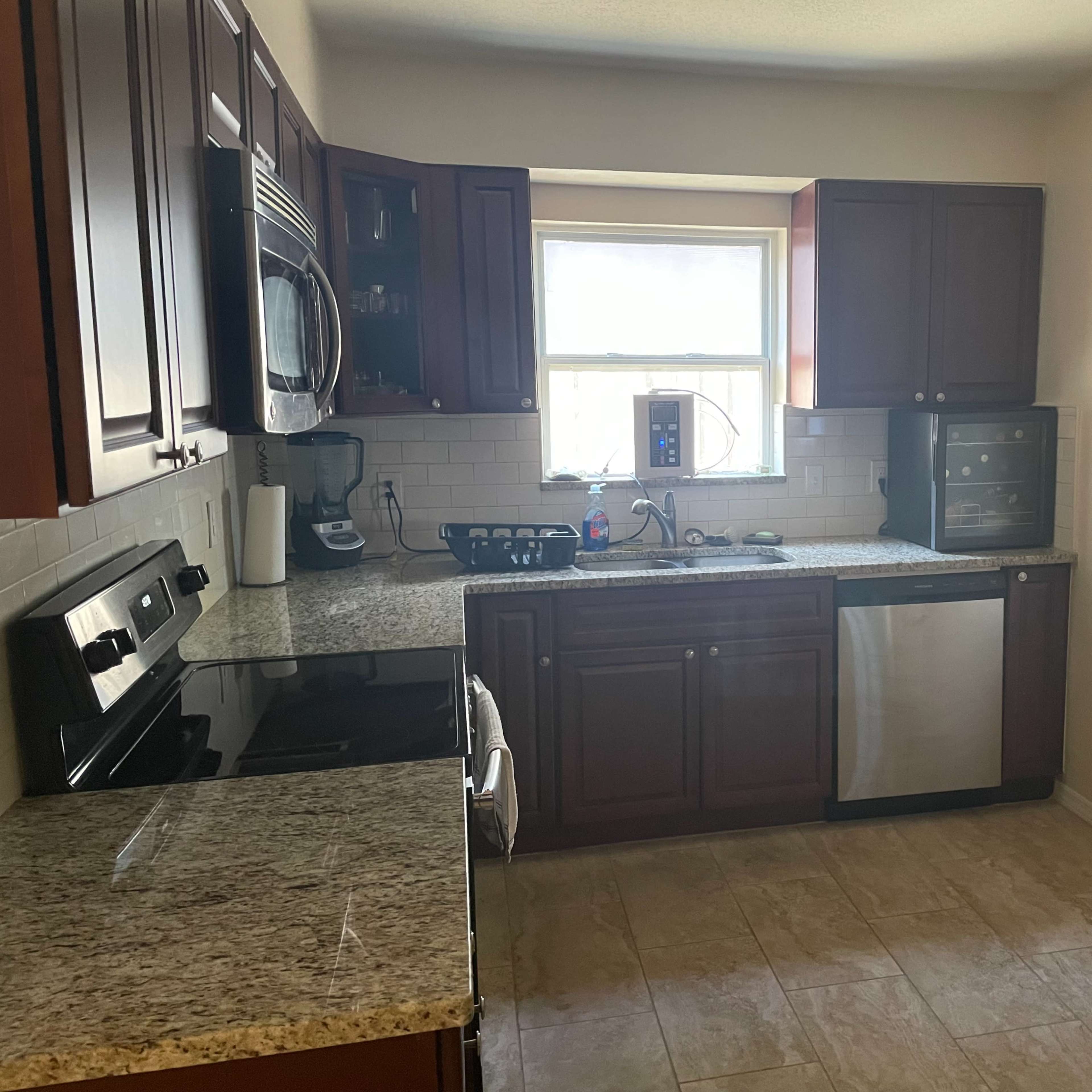 A modern kitchen features dark wooden cabinets, granite countertops, and stainless steel appliances.