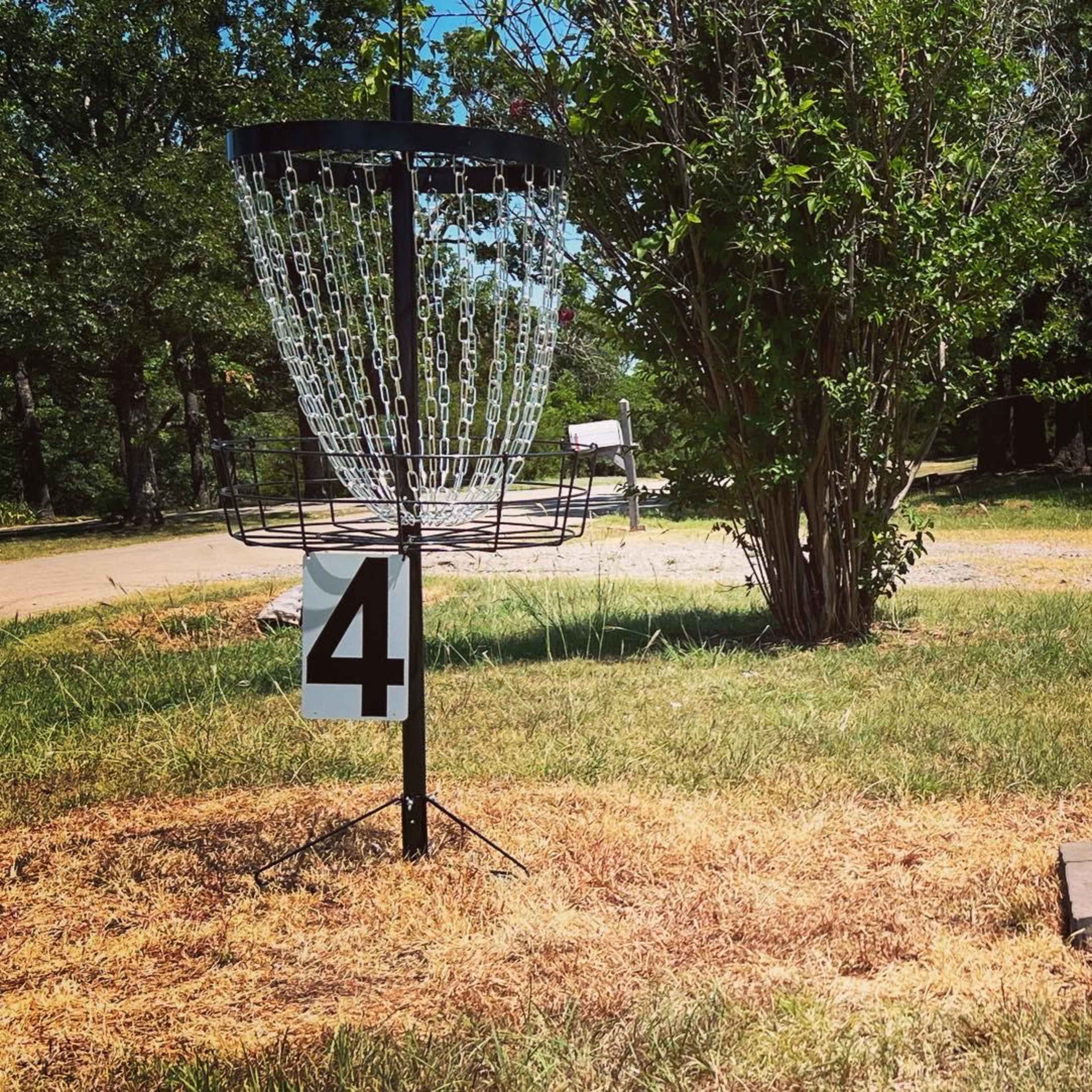 A disc golf basket positioned between two numbered markers, 4 and 5, set in a grassy area.