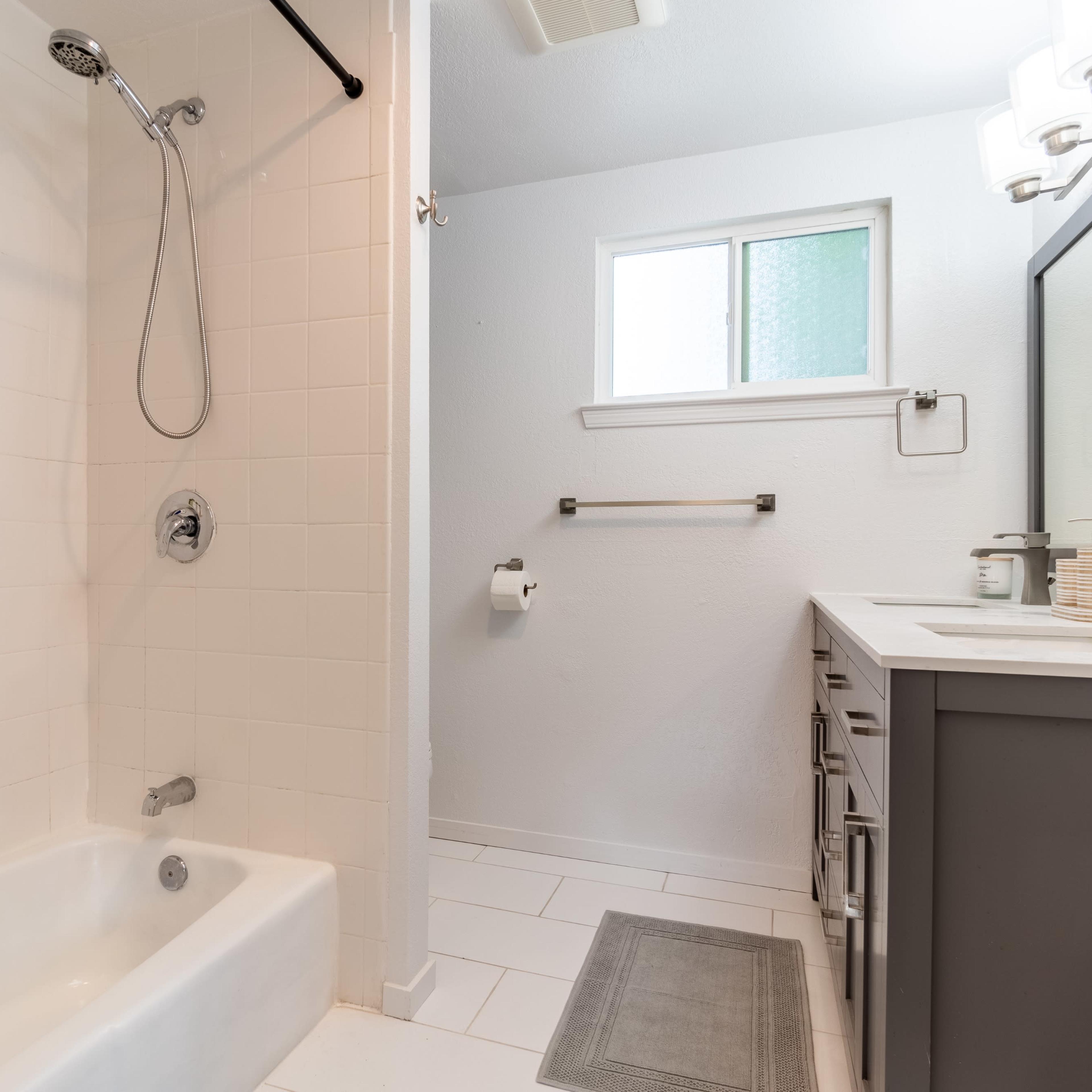 A modern bathroom with a shower area, a sink vanity, and a small window providing natural light.