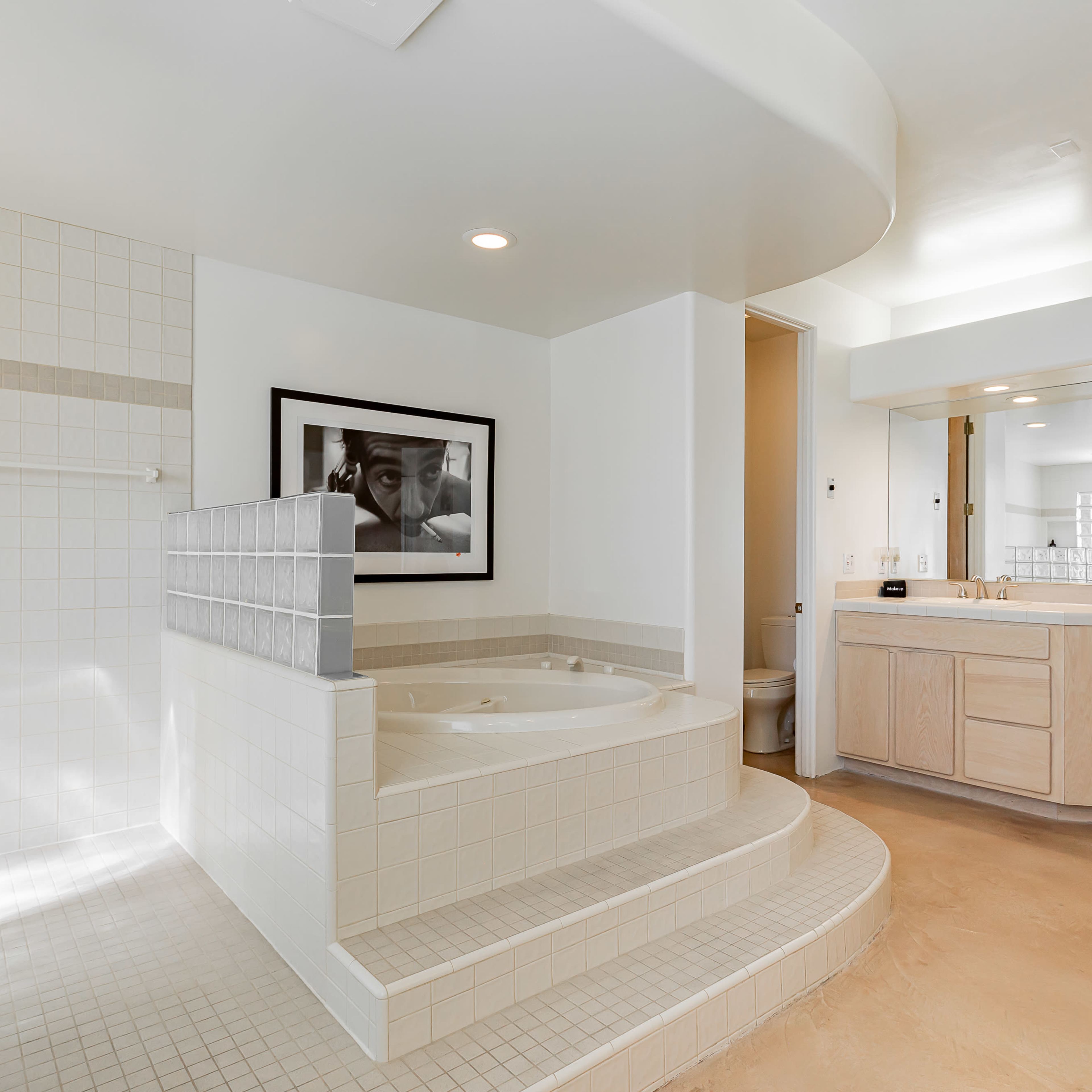 A spacious bathroom featuring a Jacuzzi tub surrounded by tiled steps and a double vanity with a mirror.