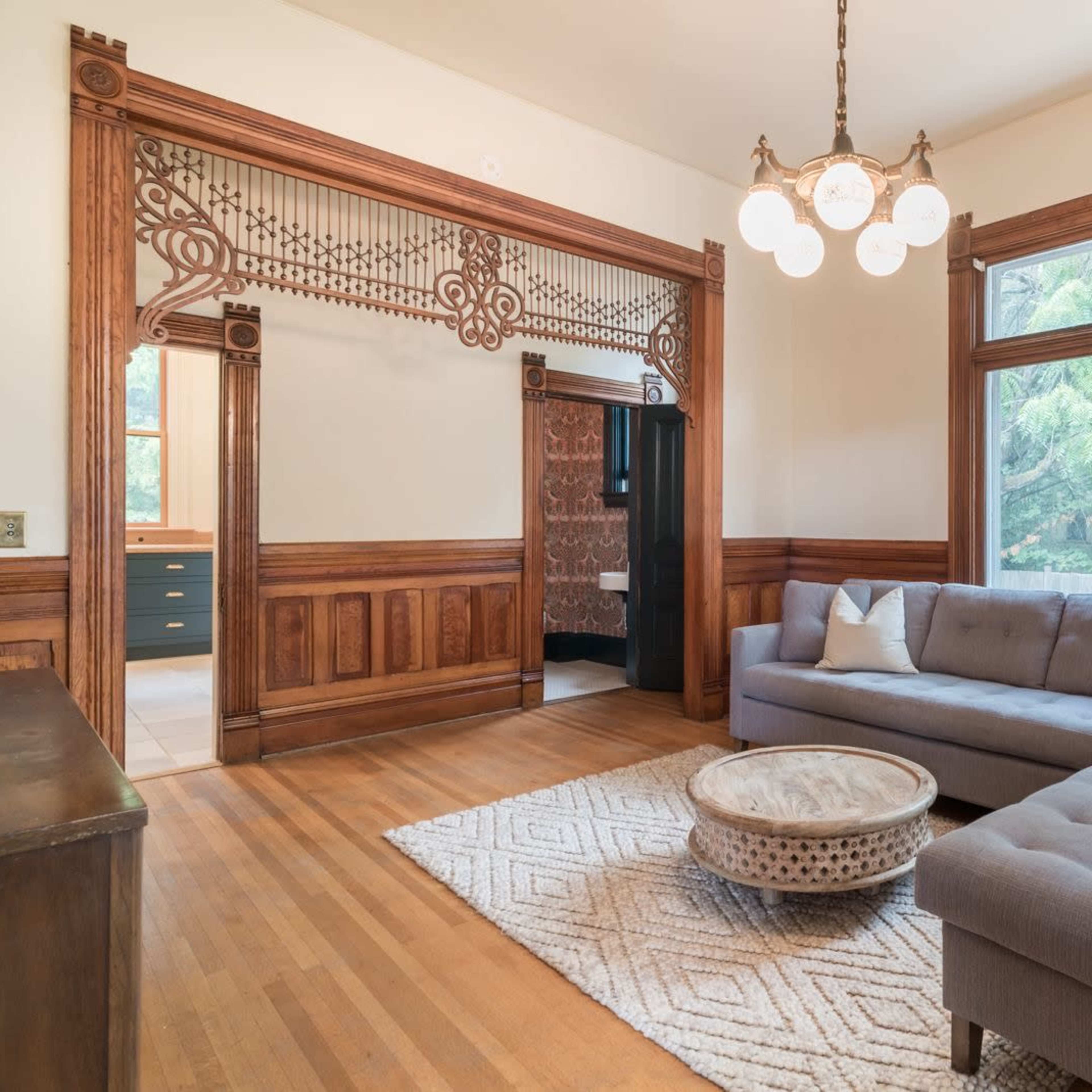 A living room featuring a gray sectional sofa, a round coffee table, and large windows that let in natural light.