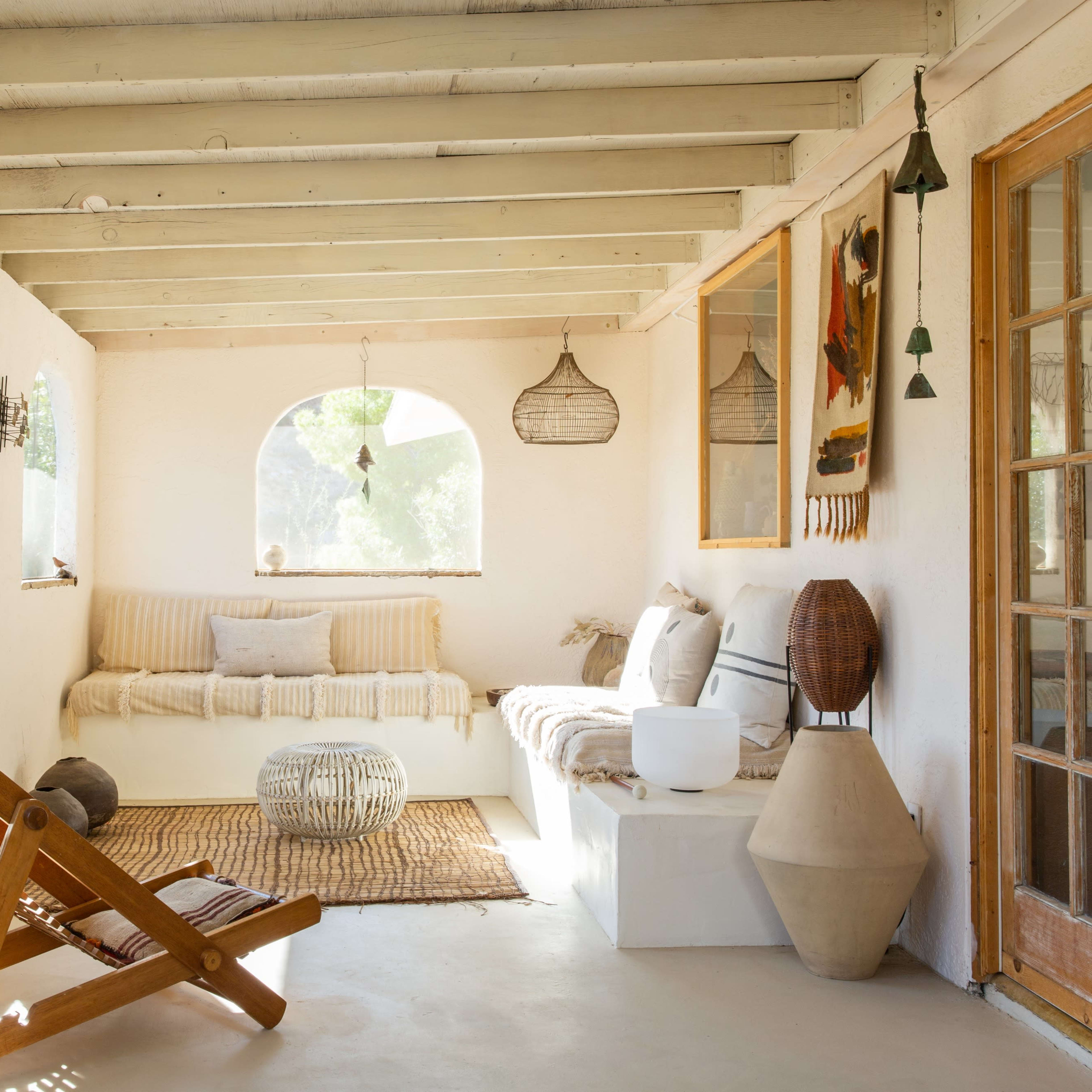 A sunlit, airy room with arched windows, a seating area with a sofa and decorative elements, and a mix of natural textures and materials.
