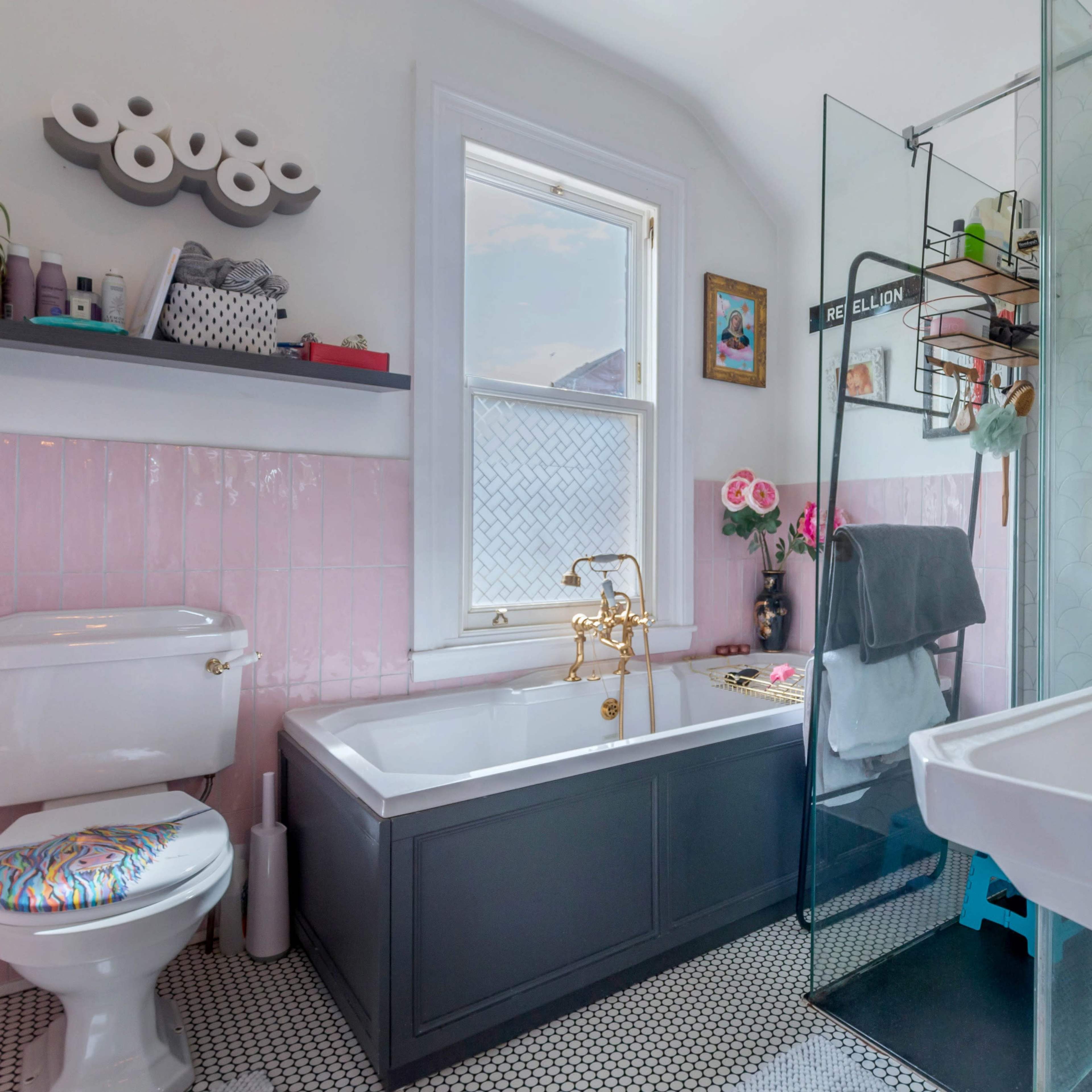 A bright bathroom featuring a freestanding bathtub, a glass shower, a dual-sink vanity, and decorative plants.