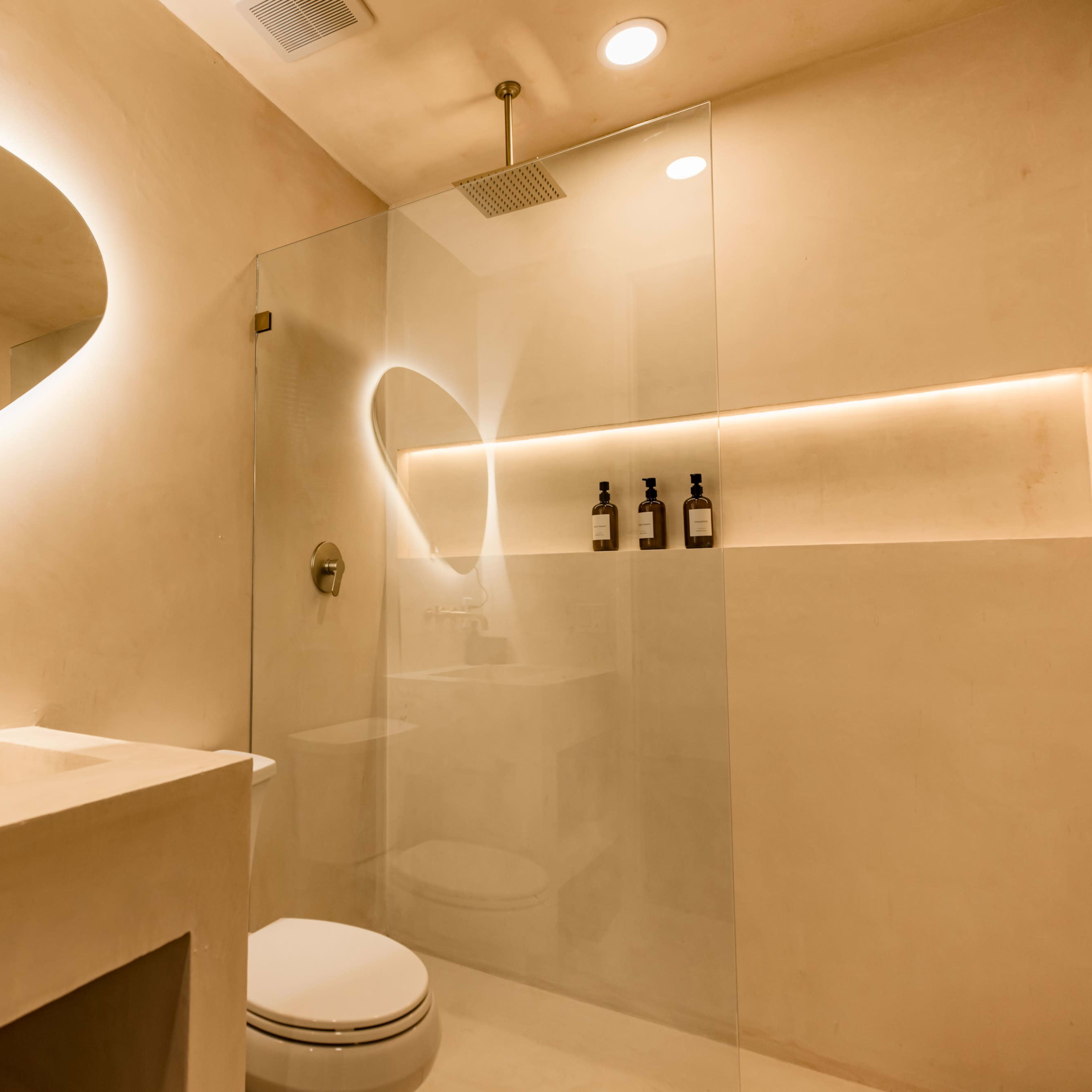 A modern bathroom features a minimalist design with a glass shower, a wall-mounted mirror, and recessed lighting.