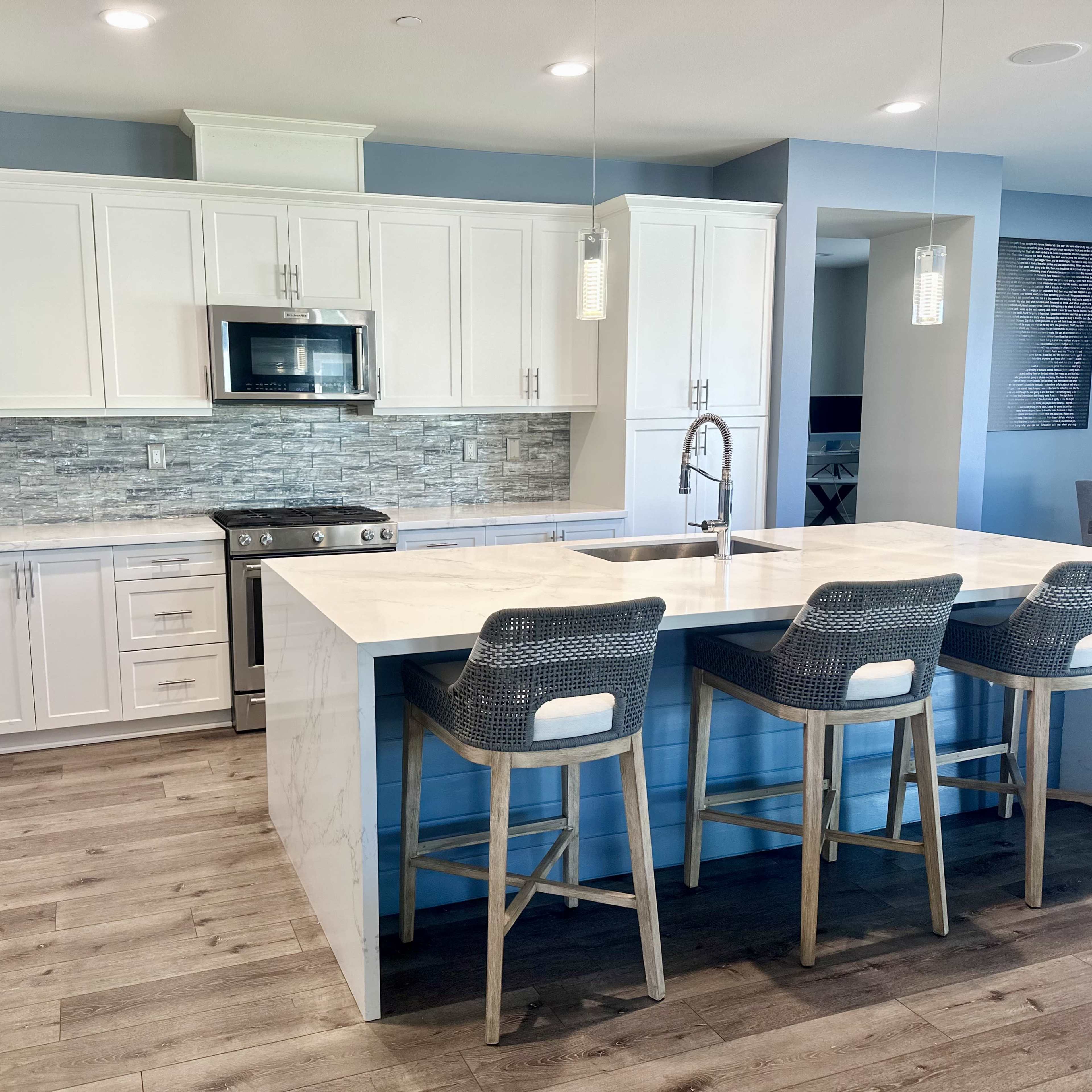 A modern kitchen featuring white cabinetry, stainless steel appliances, and a large island with bar seating.