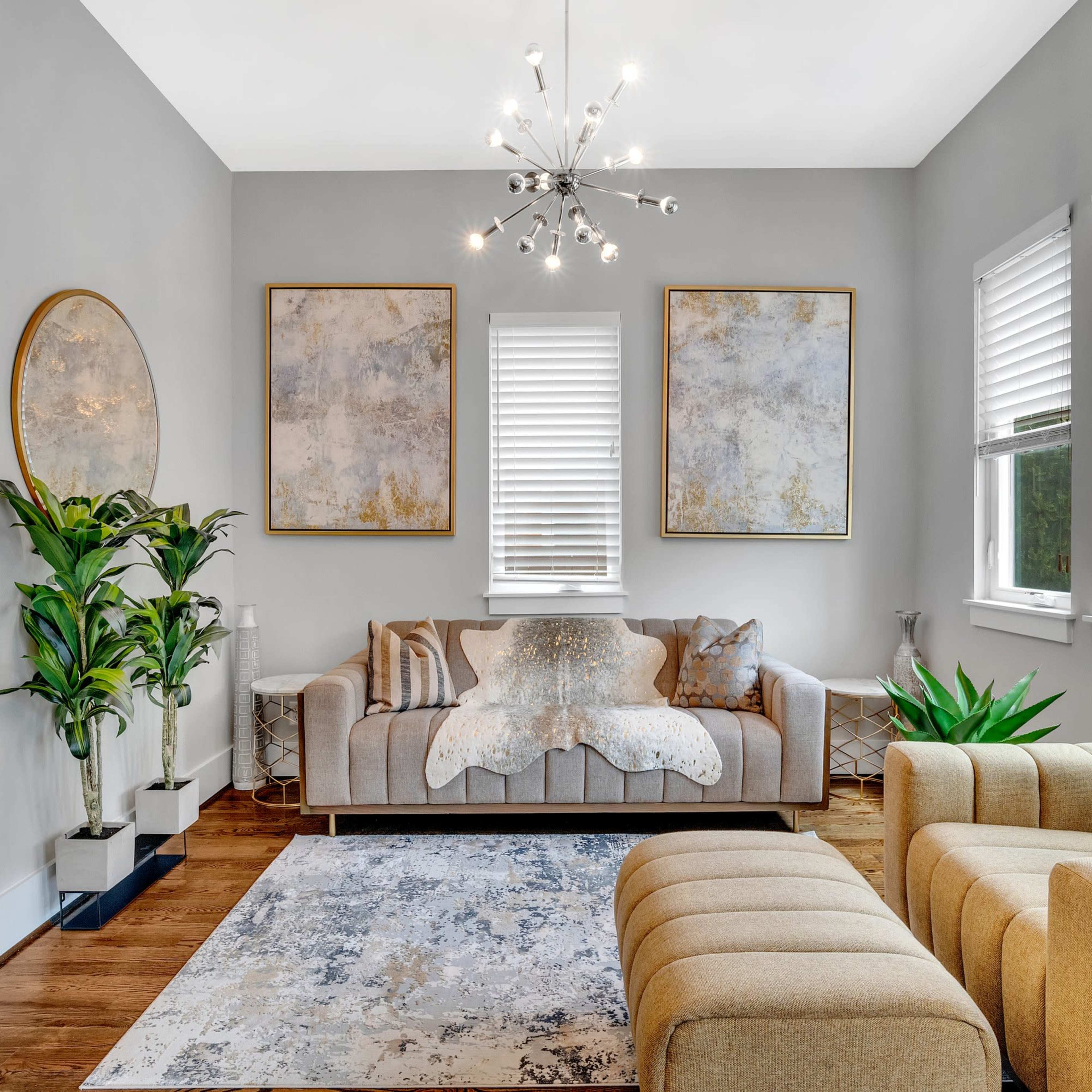 The living room features a modern design with a gray color scheme, a sofa with decorative pillows, a paired armchair, and two large paintings on the walls.