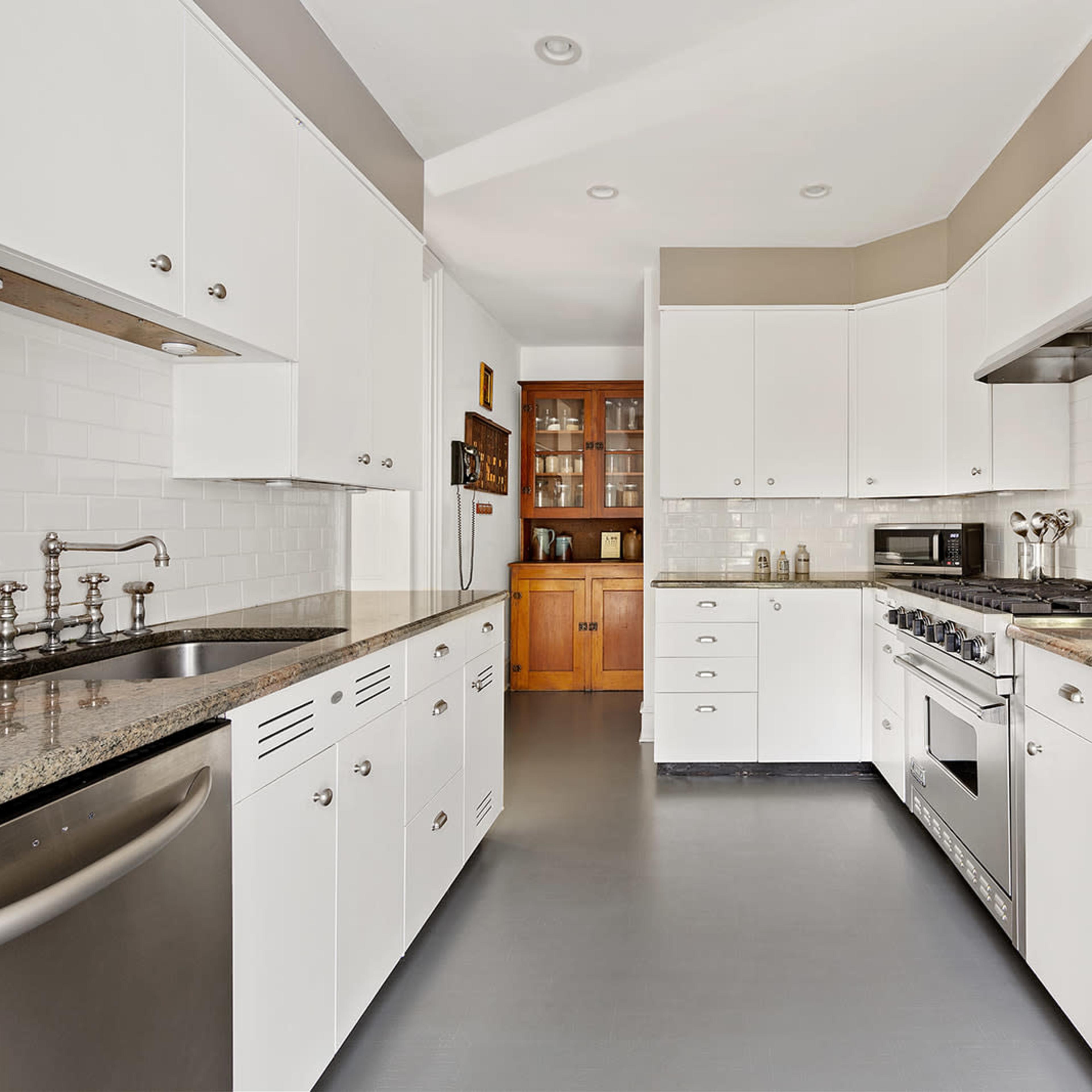 A modern kitchen featuring white cabinetry, granite countertops, and stainless steel appliances.