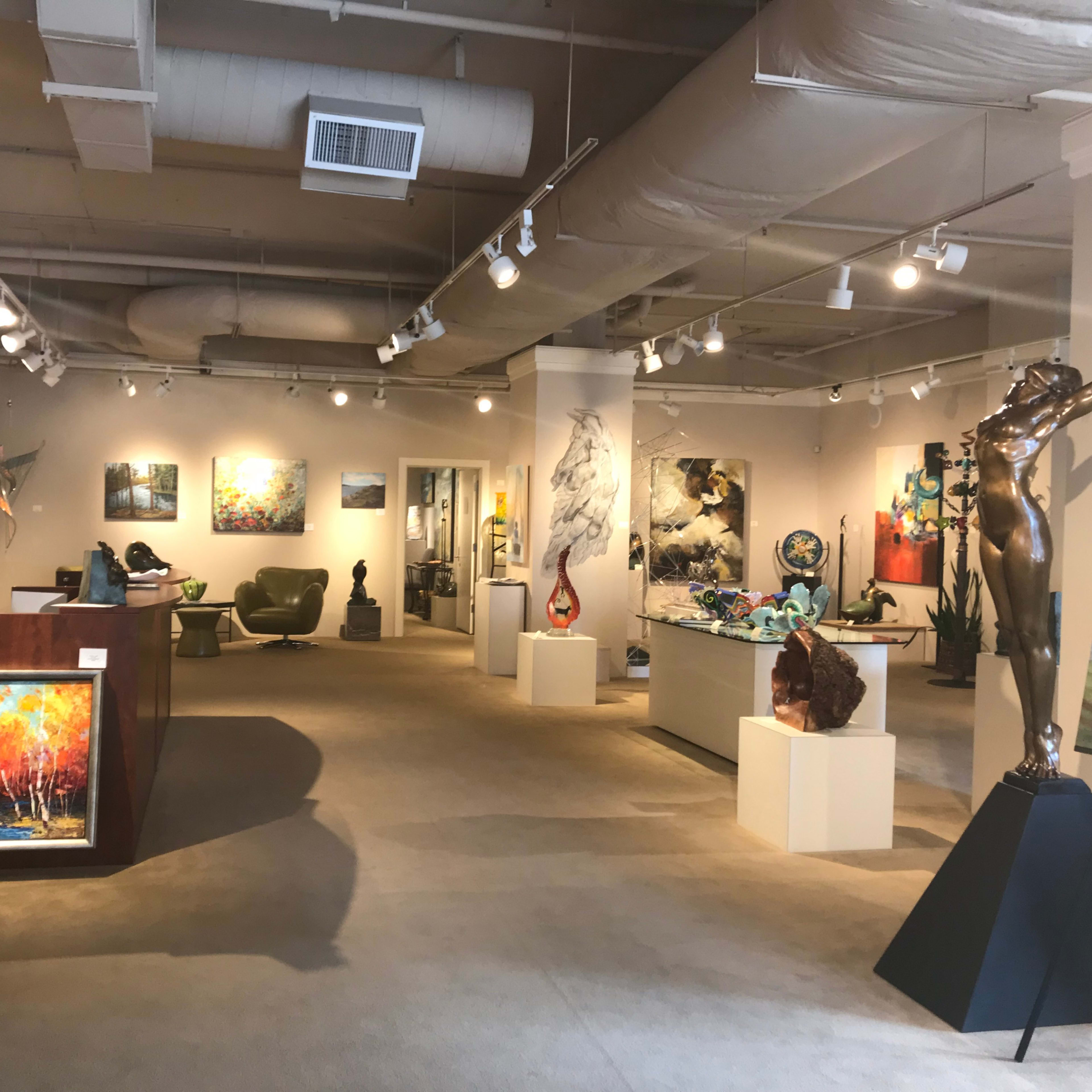 An art gallery featuring a variety of paintings and sculptures displayed throughout the spacious room.