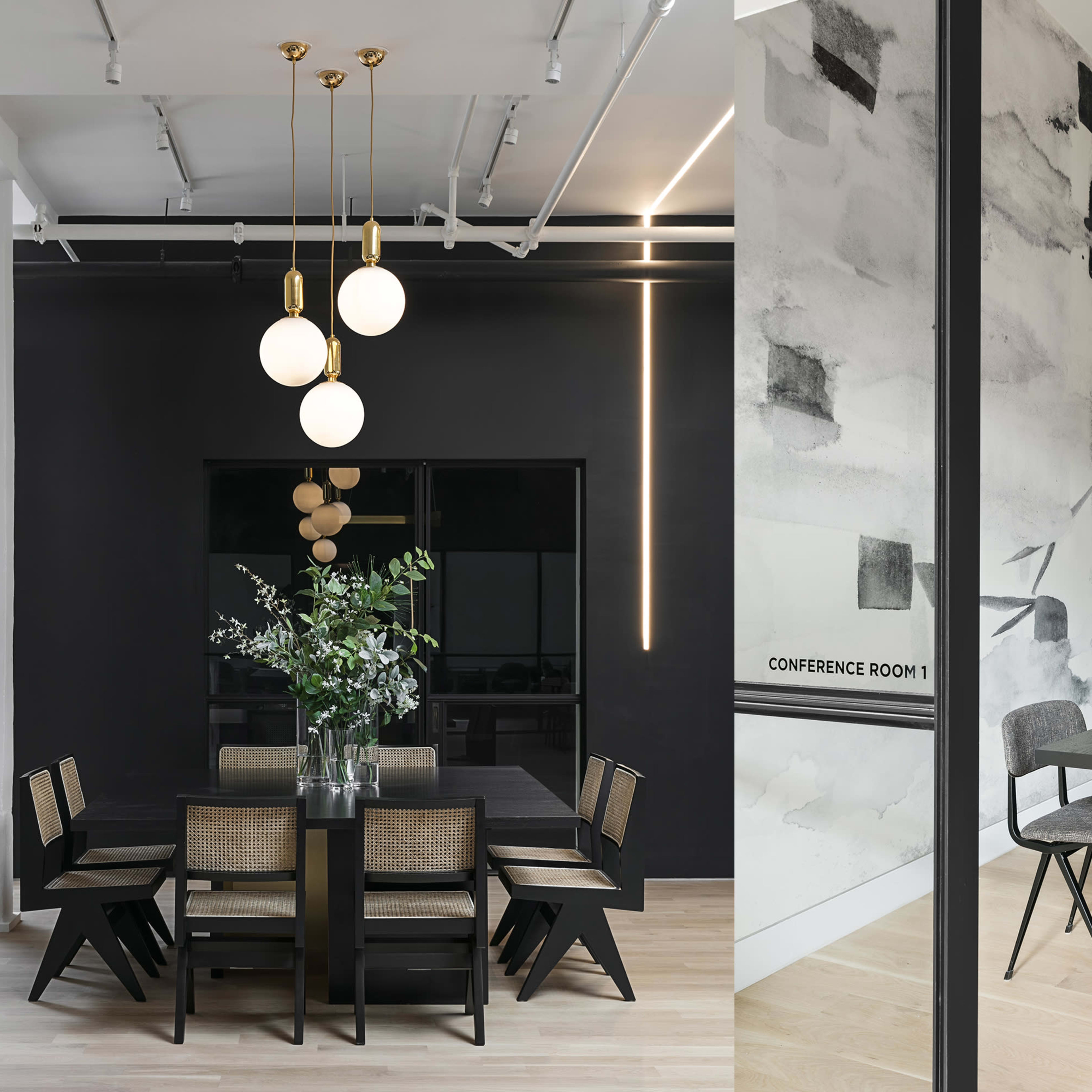 Two modern conference rooms, one with a large black table surrounded by six chairs and decorative lighting, and the other with a long table, minimalist decor, and a TV on the wall.