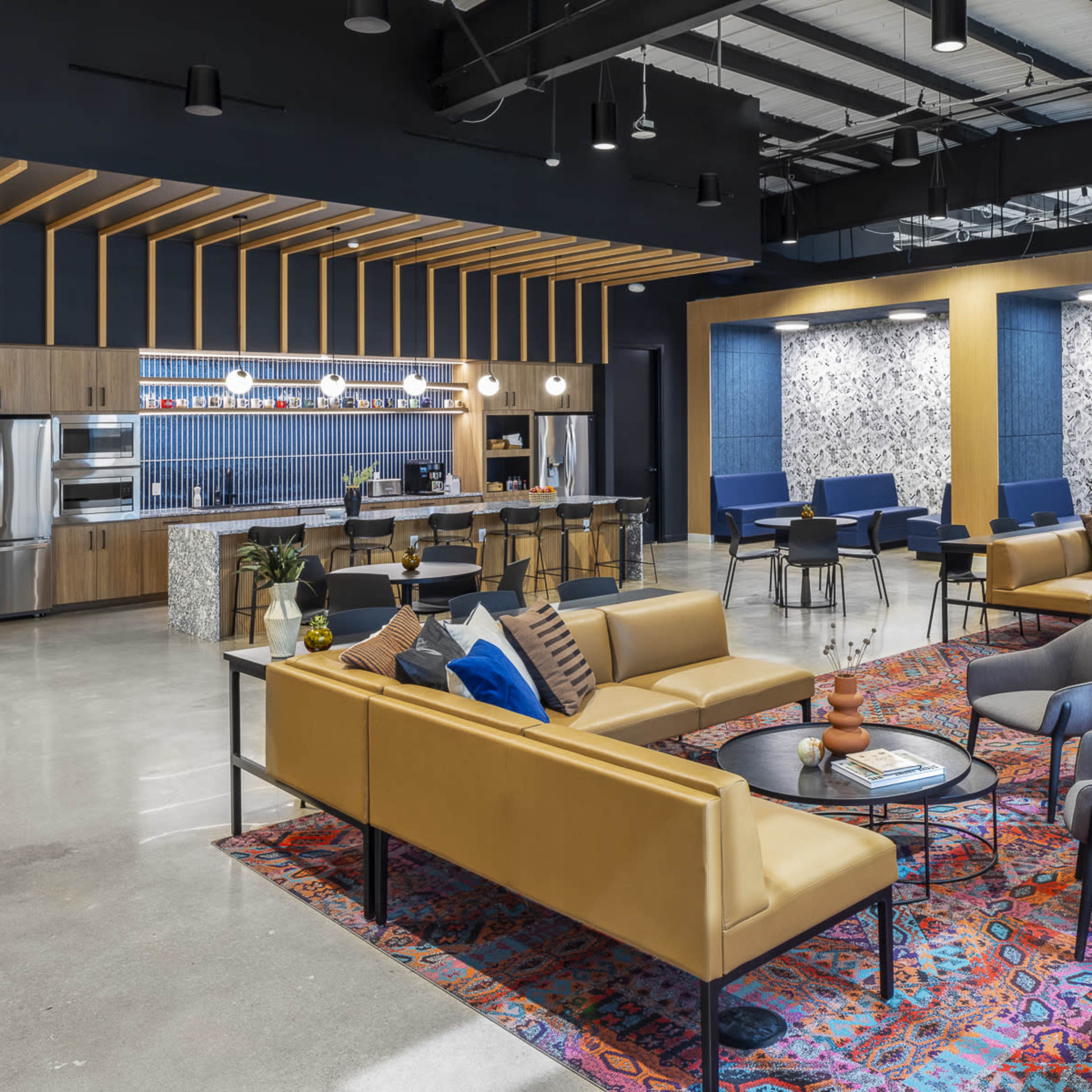 A modern lounge area features a mix of seating arrangements, a kitchen bar, and decorative walls with patterned accents.