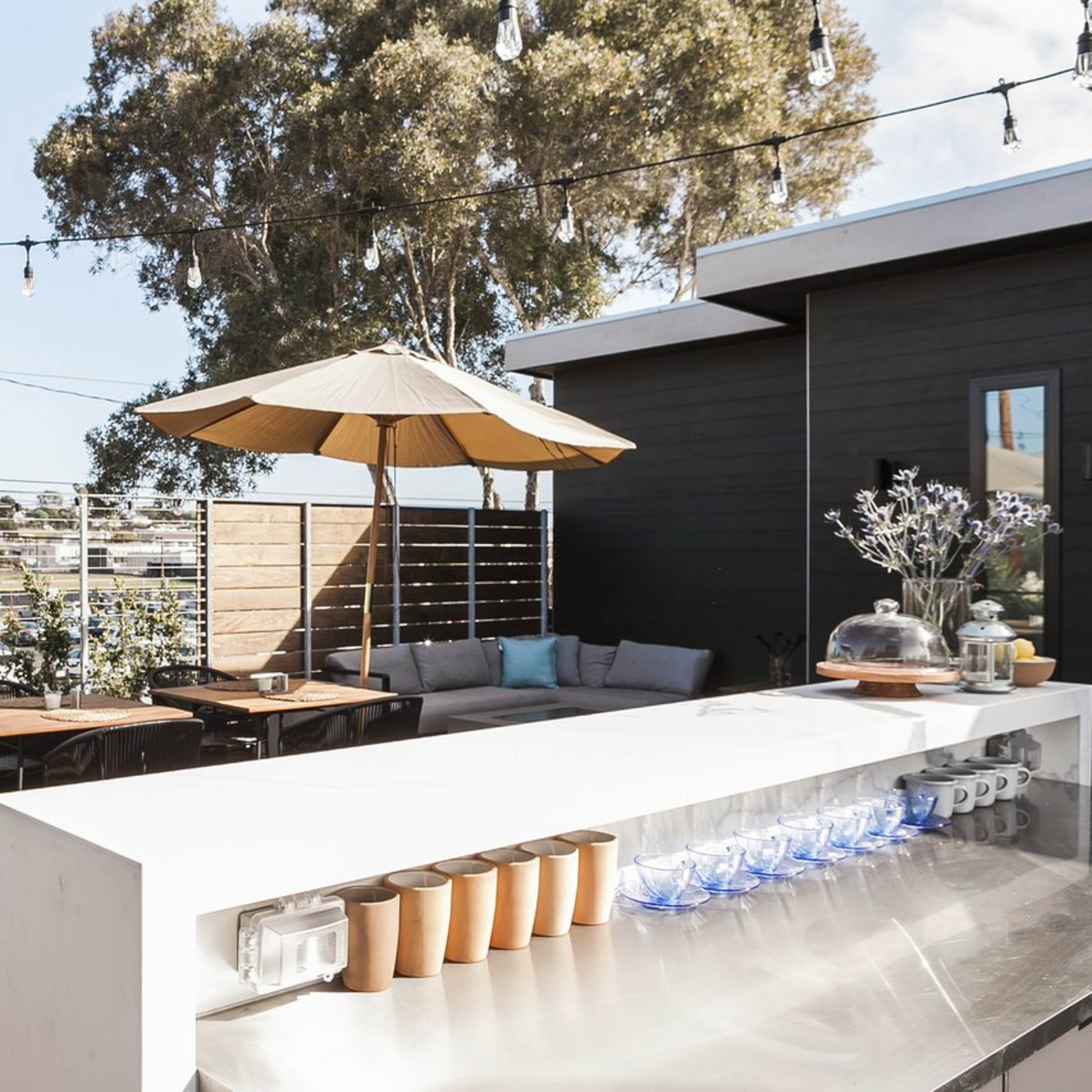 A rooftop terrace with tables, chairs, and umbrellas, overlooking a water view.