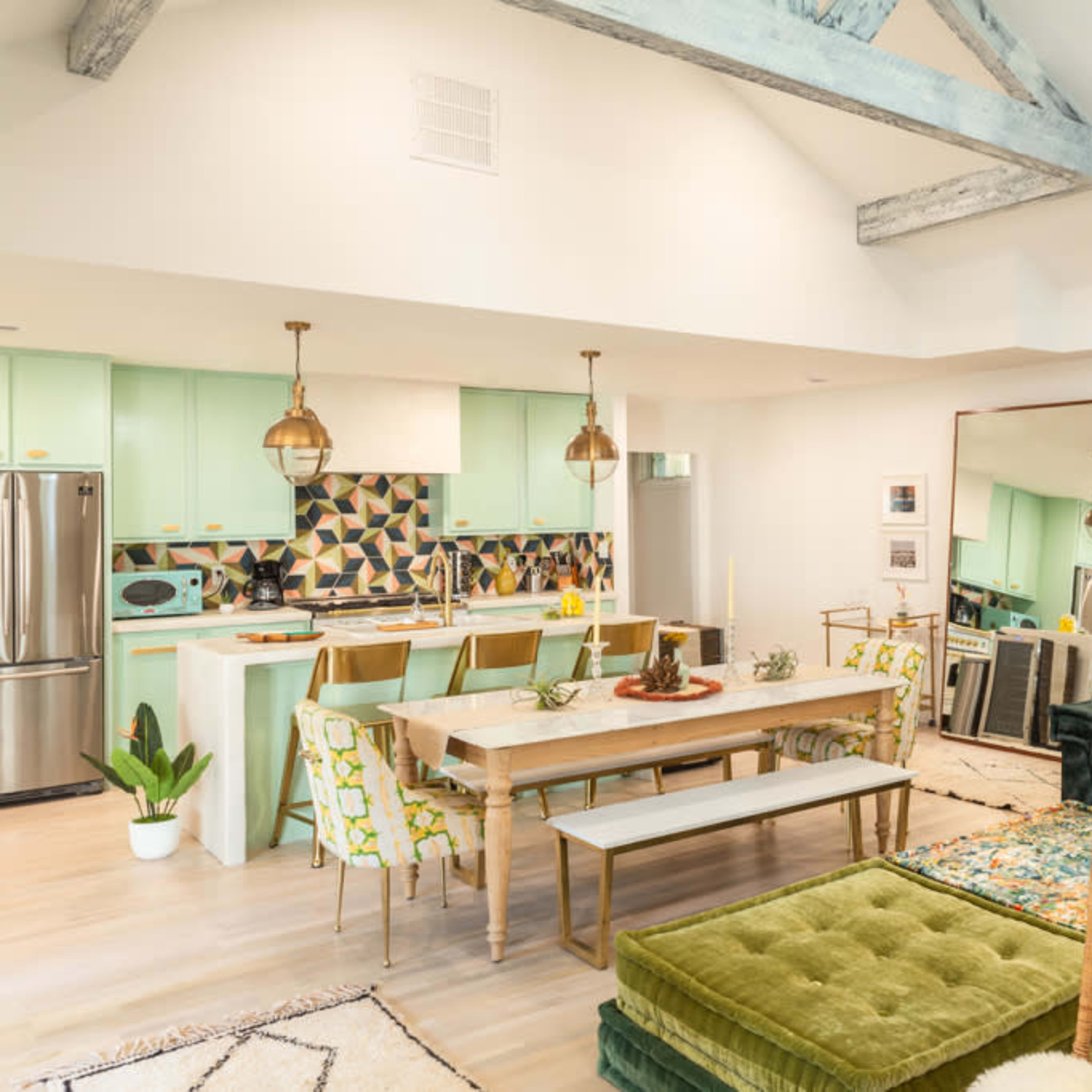 A modern living space with a kitchen, dining area, and a seating area featuring vibrant decor and a mix of seating options.