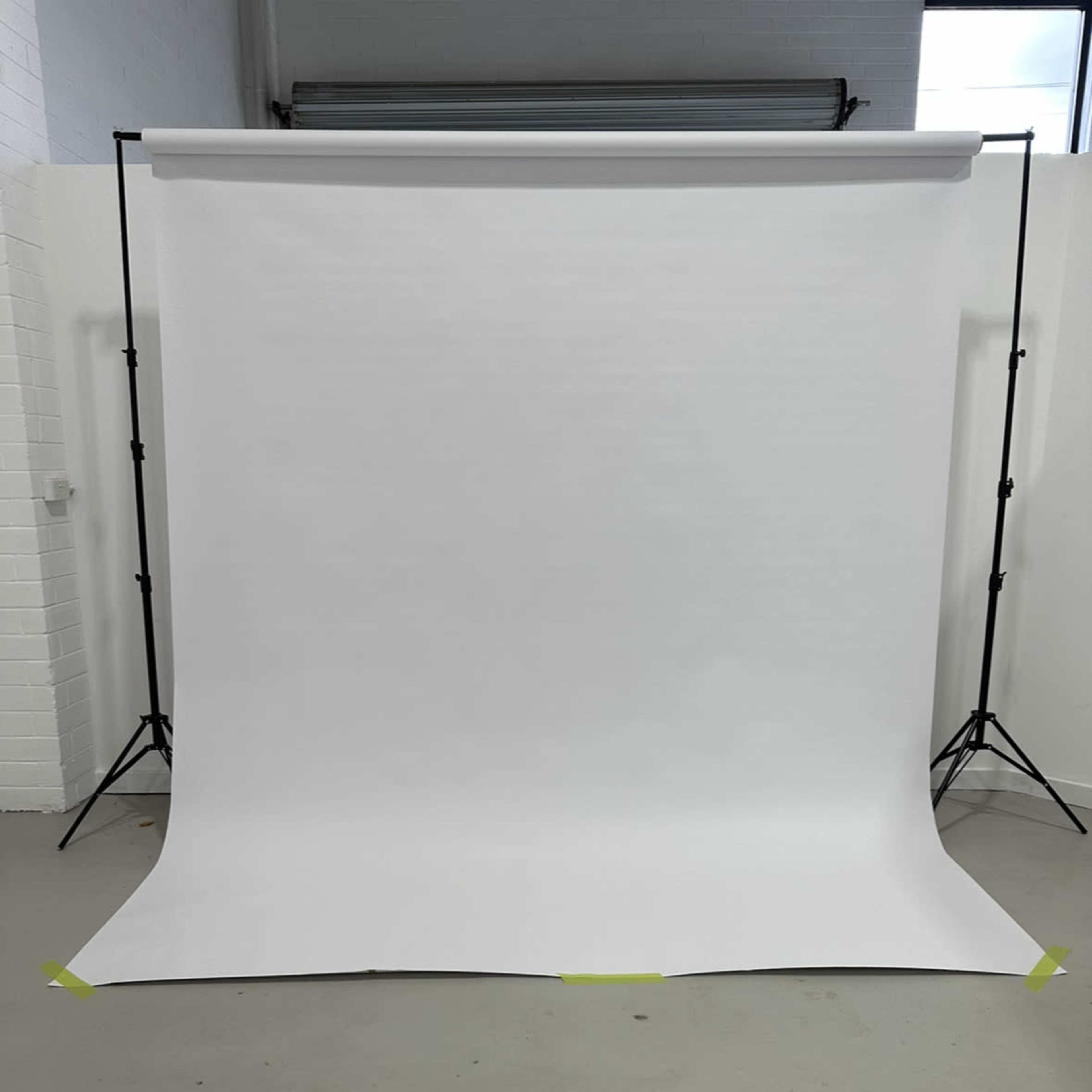 A blank white backdrop set up on stands in a studio environment.