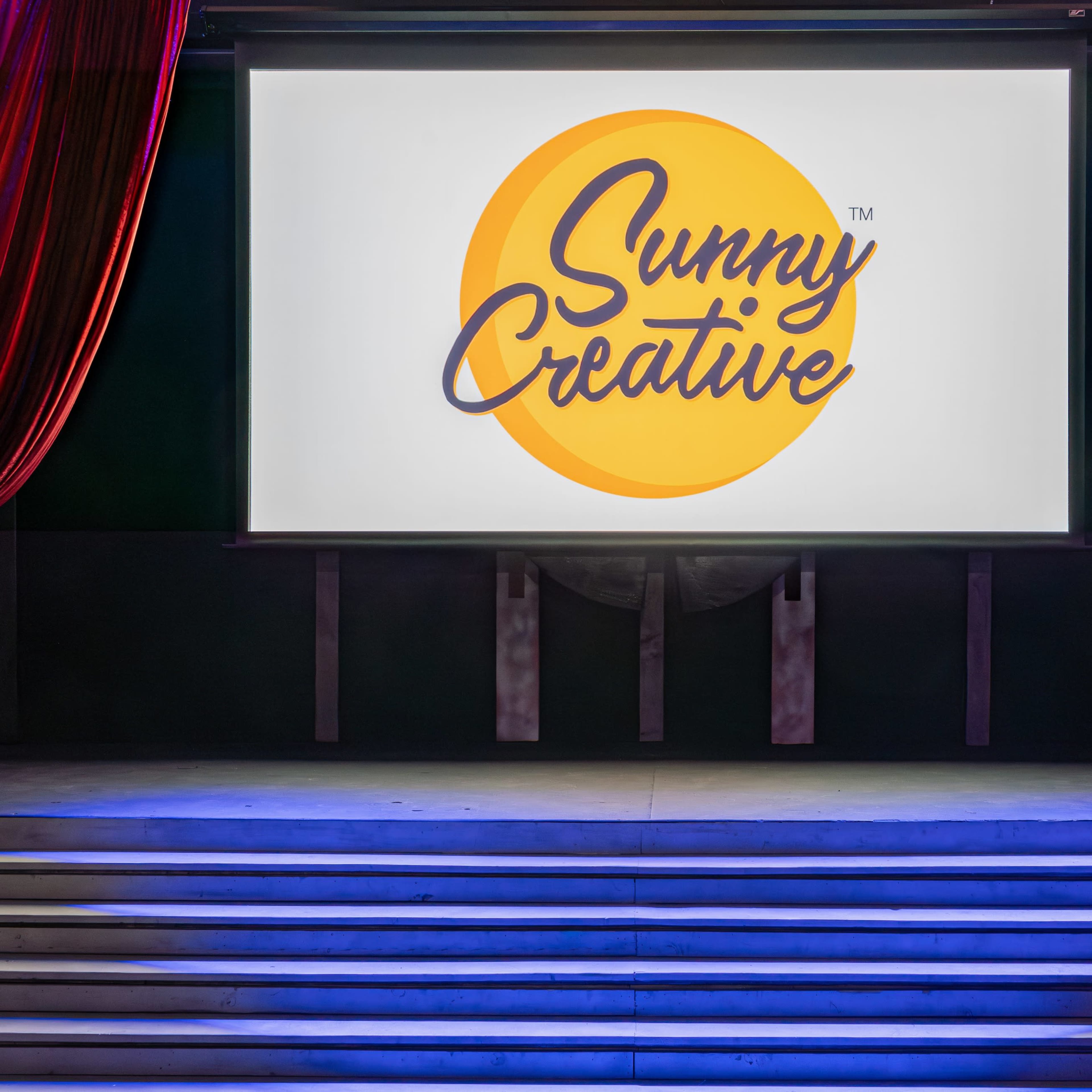 A stage with red curtains, featuring a large screen displaying the logo for "Sunny Creative."