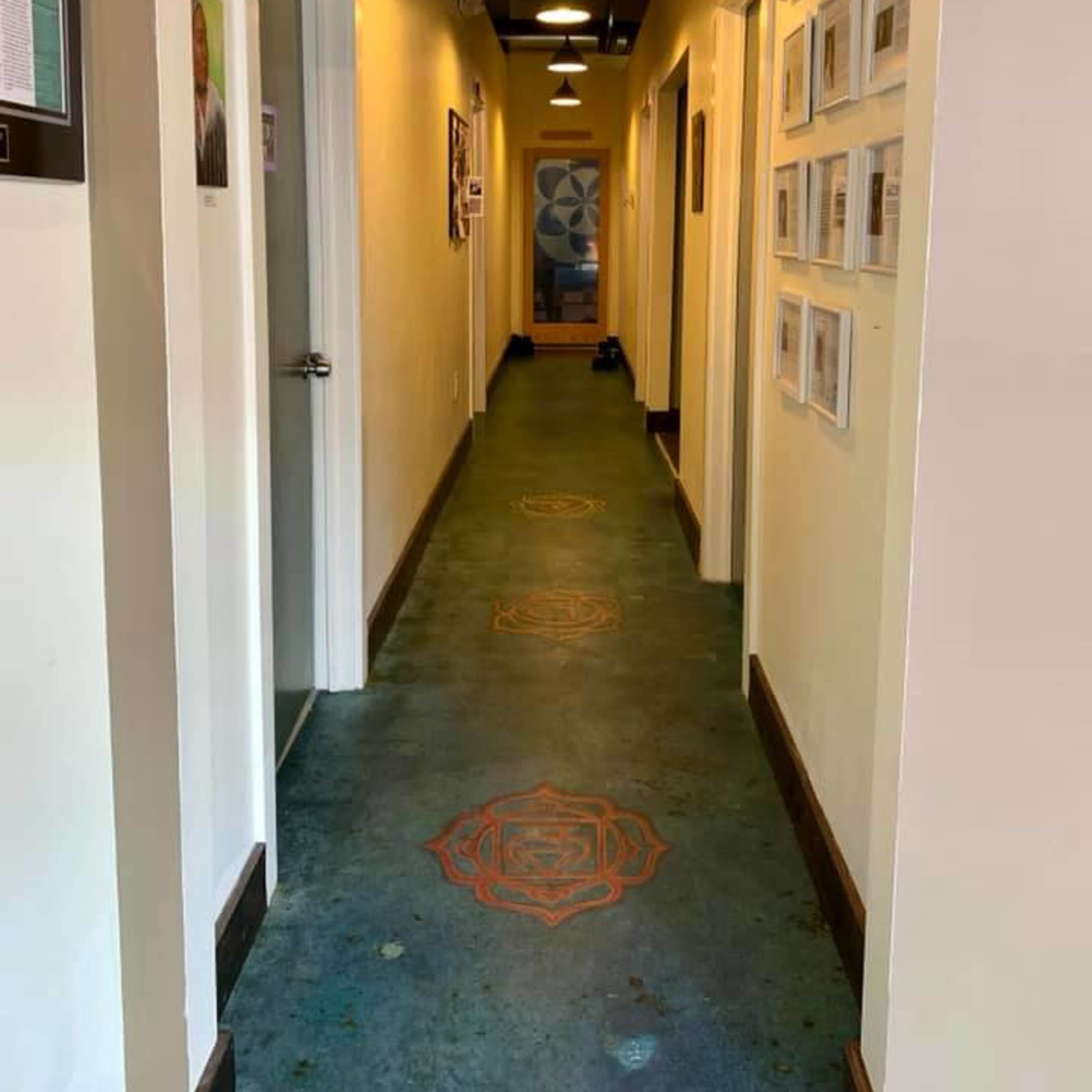 A narrow hallway lined with doors on either side and framed photographs on the wall.