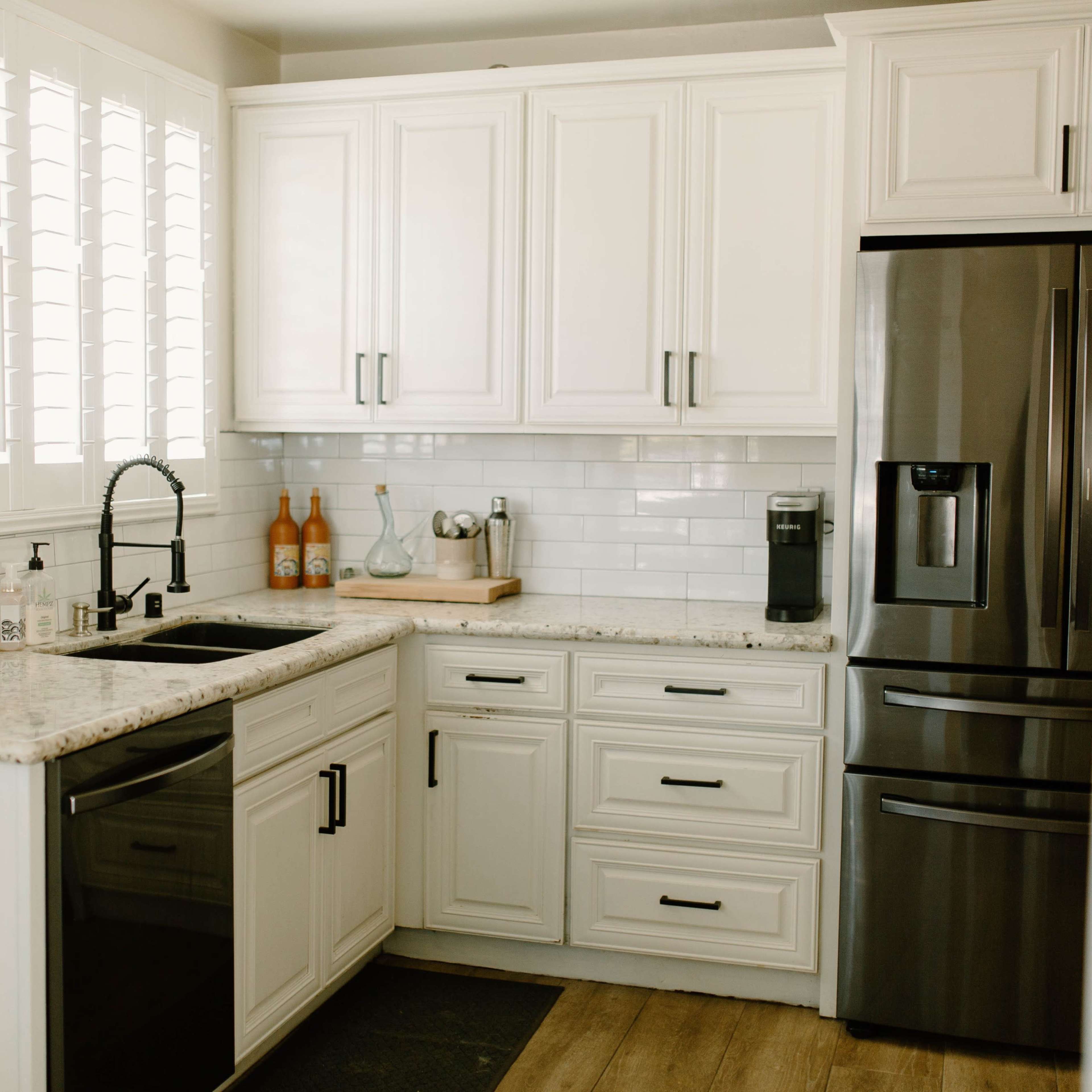 A modern kitchen with white cabinetry, a dark stainless steel refrigerator, and a black sink.