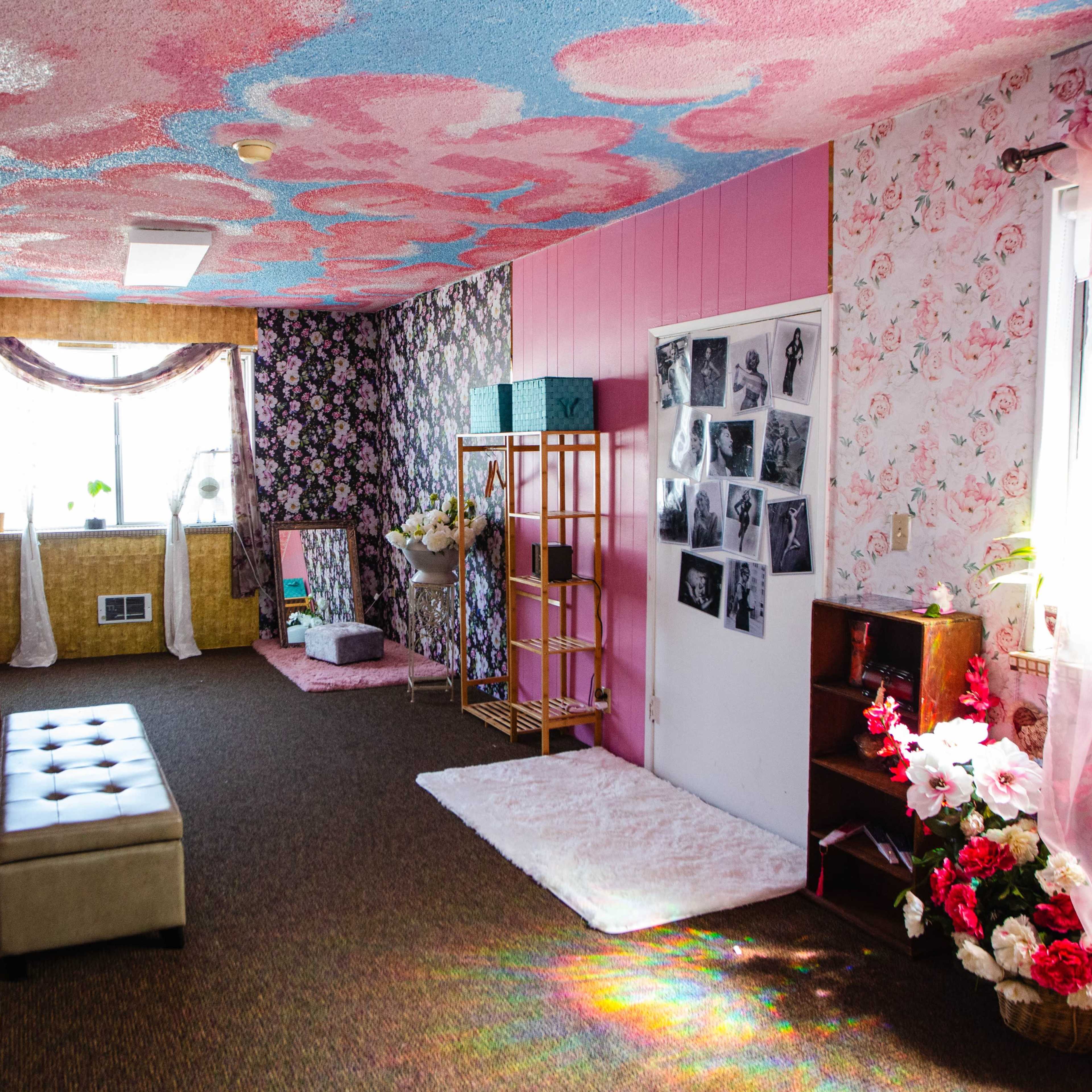 A brightly decorated interior room with floral wallpaper, a colorful ceiling, and various furniture pieces arranged throughout the space.