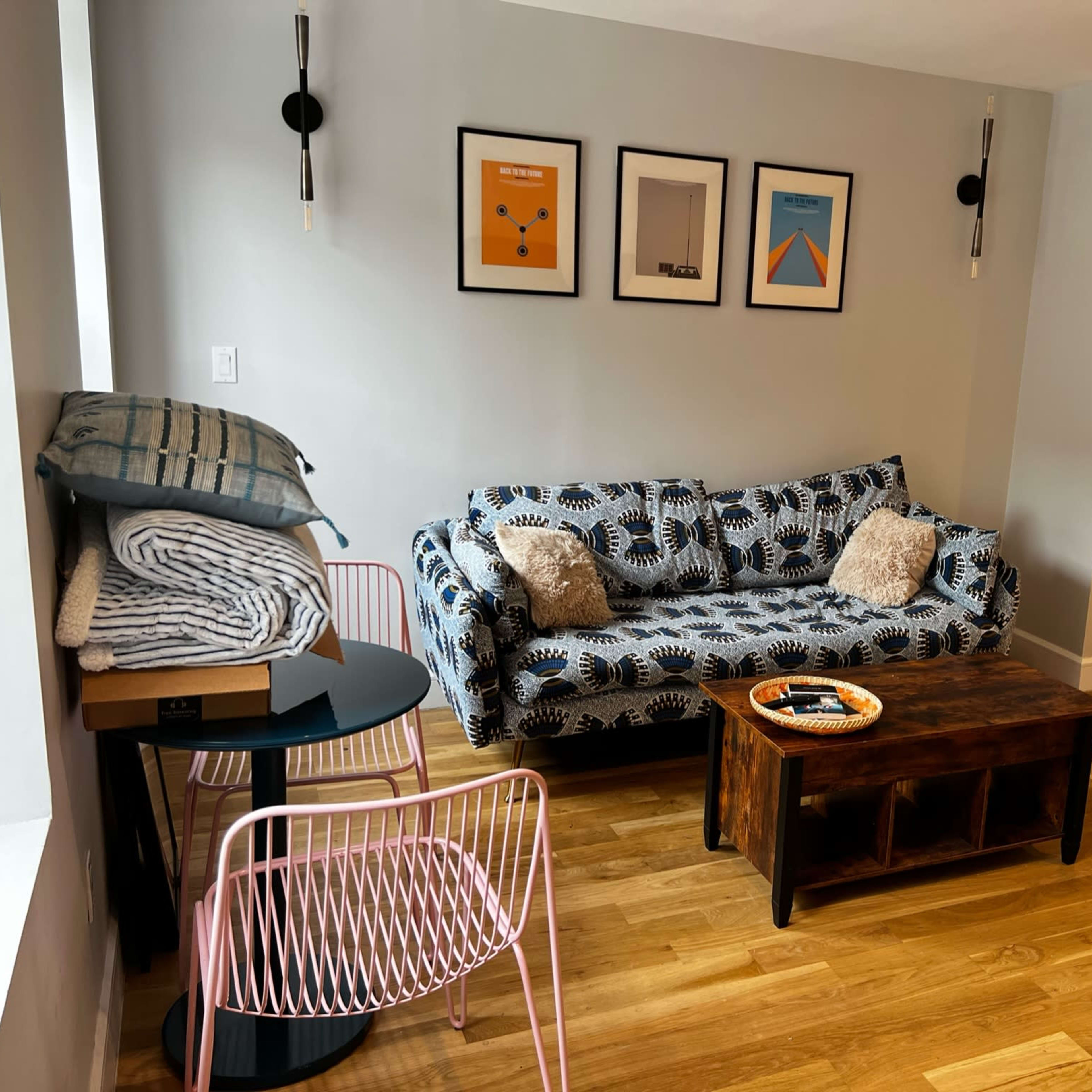A modern living room featuring a patterned couch, a wooden coffee table, and framed artwork on the wall.