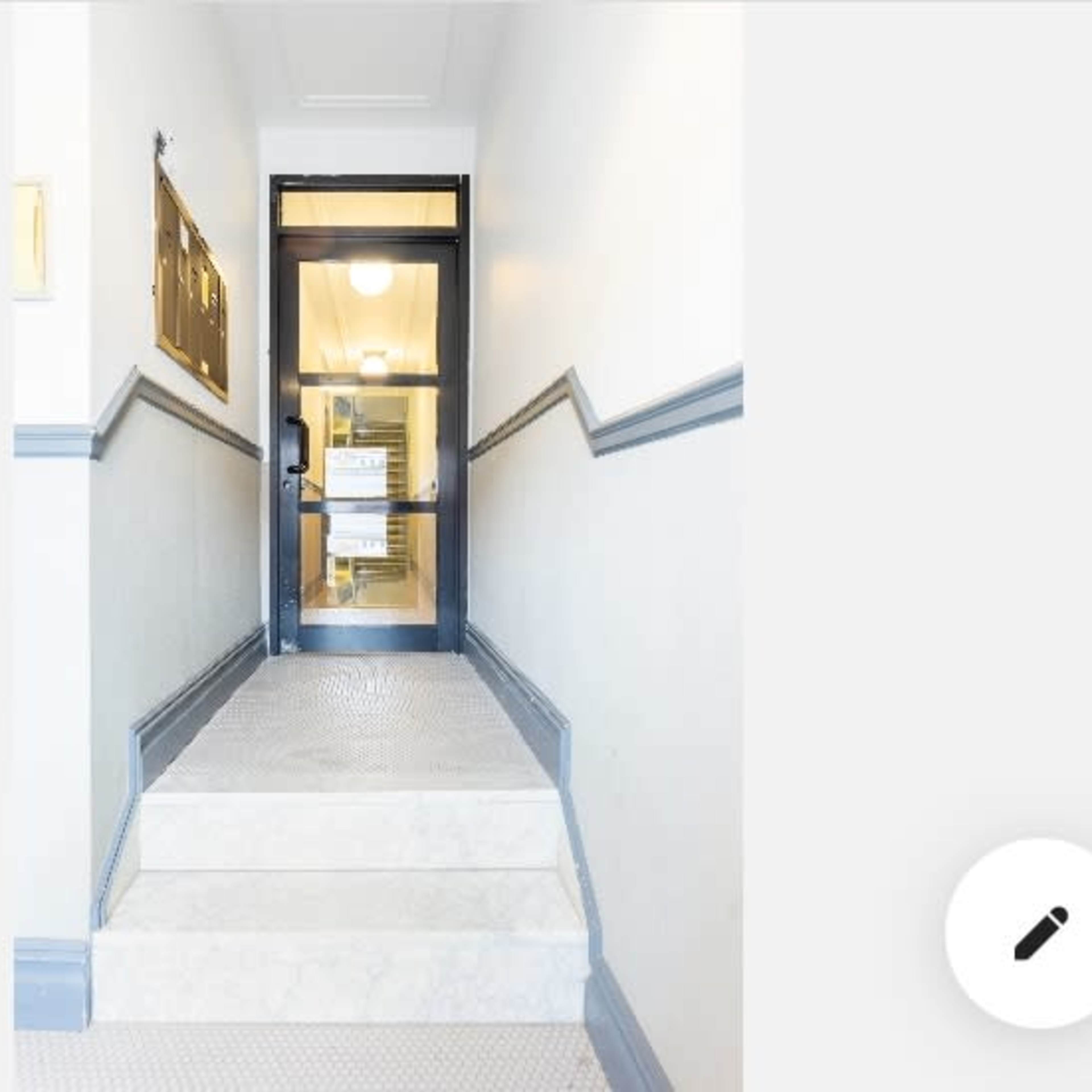 A set of stairs leads up to a glass door located at the top, with a notice posted on it.