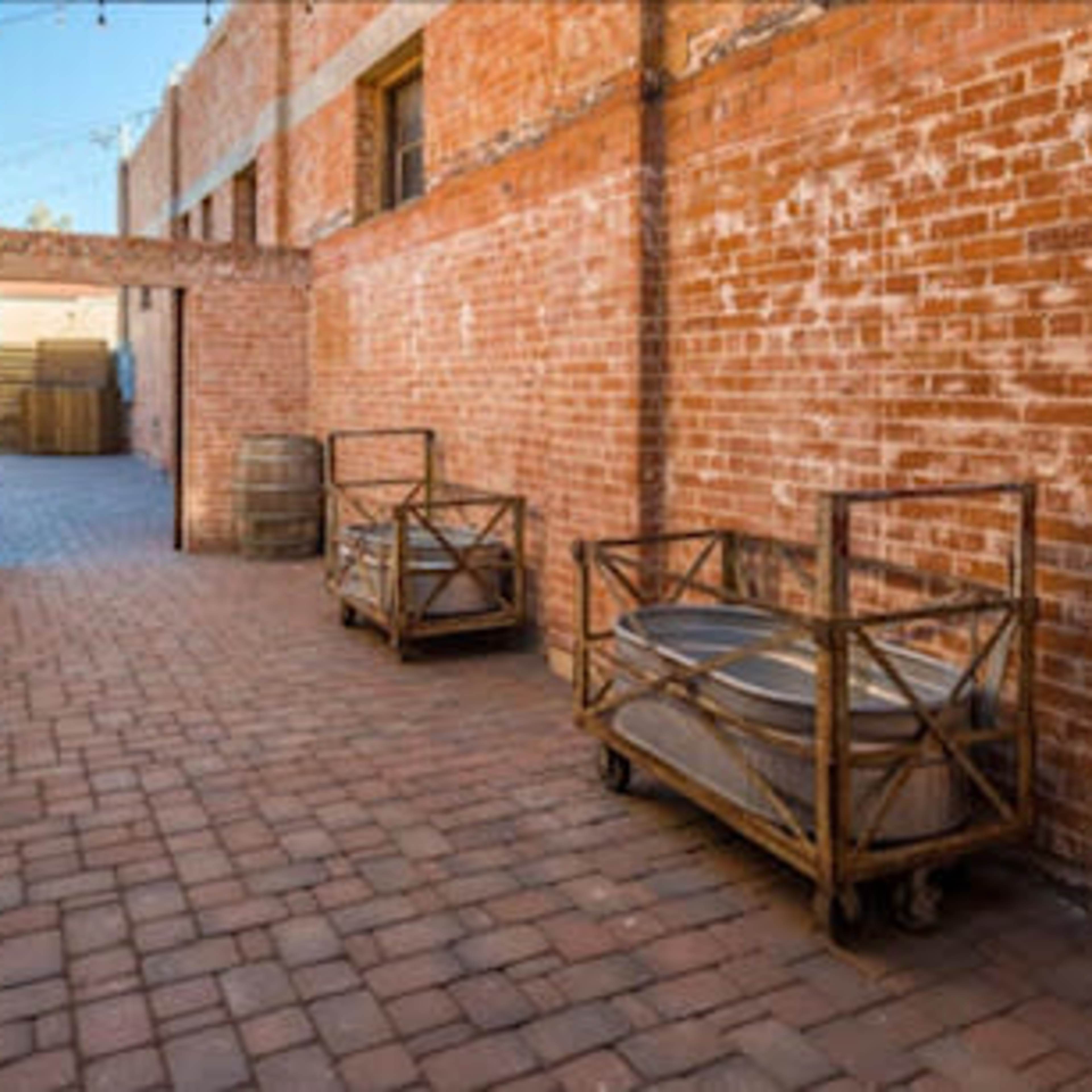 A brick-paved alleyway lined with brick walls and two wooden carts on wheels.