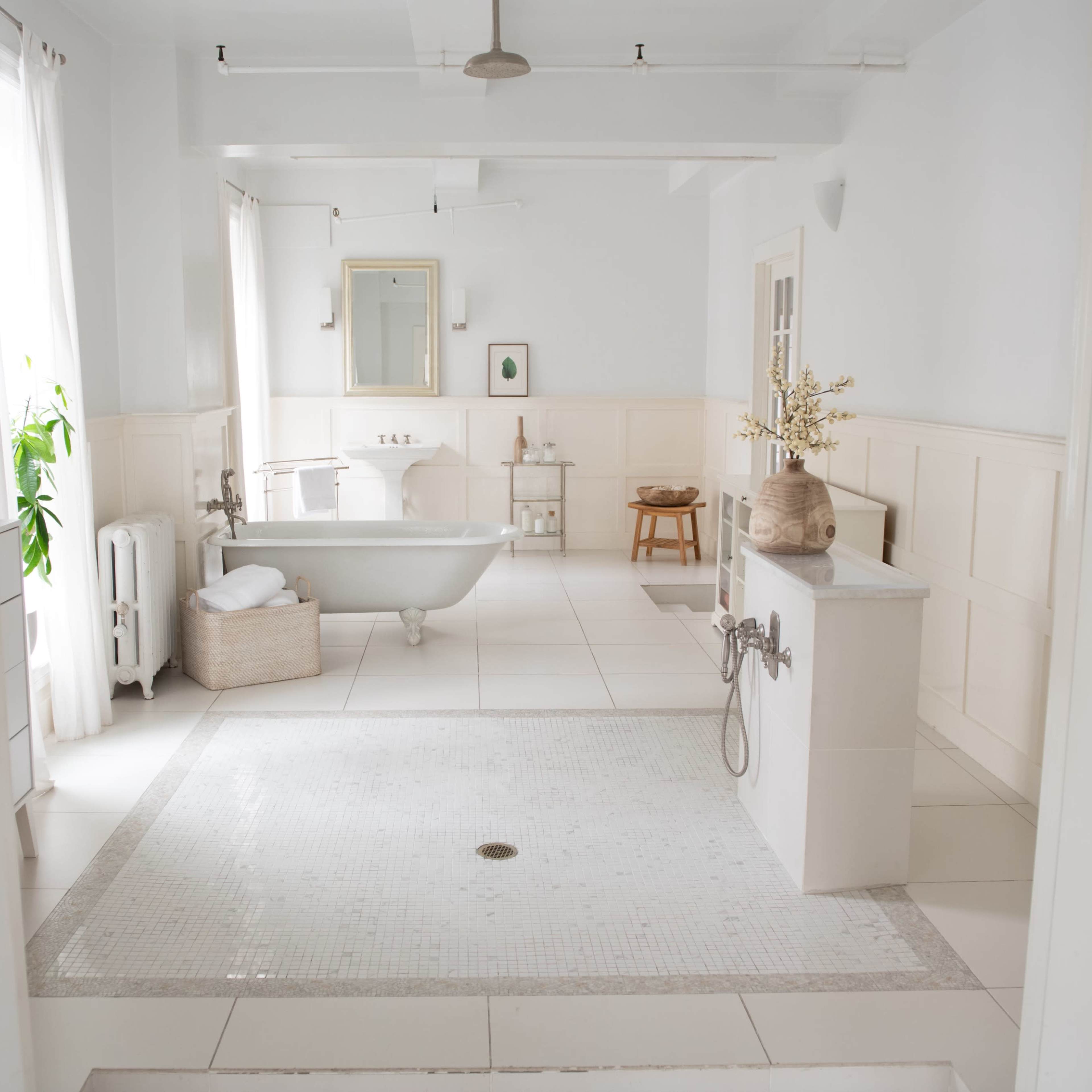 A spacious bathroom features a freestanding bathtub, a tiled floor, and large windows allowing natural light.
