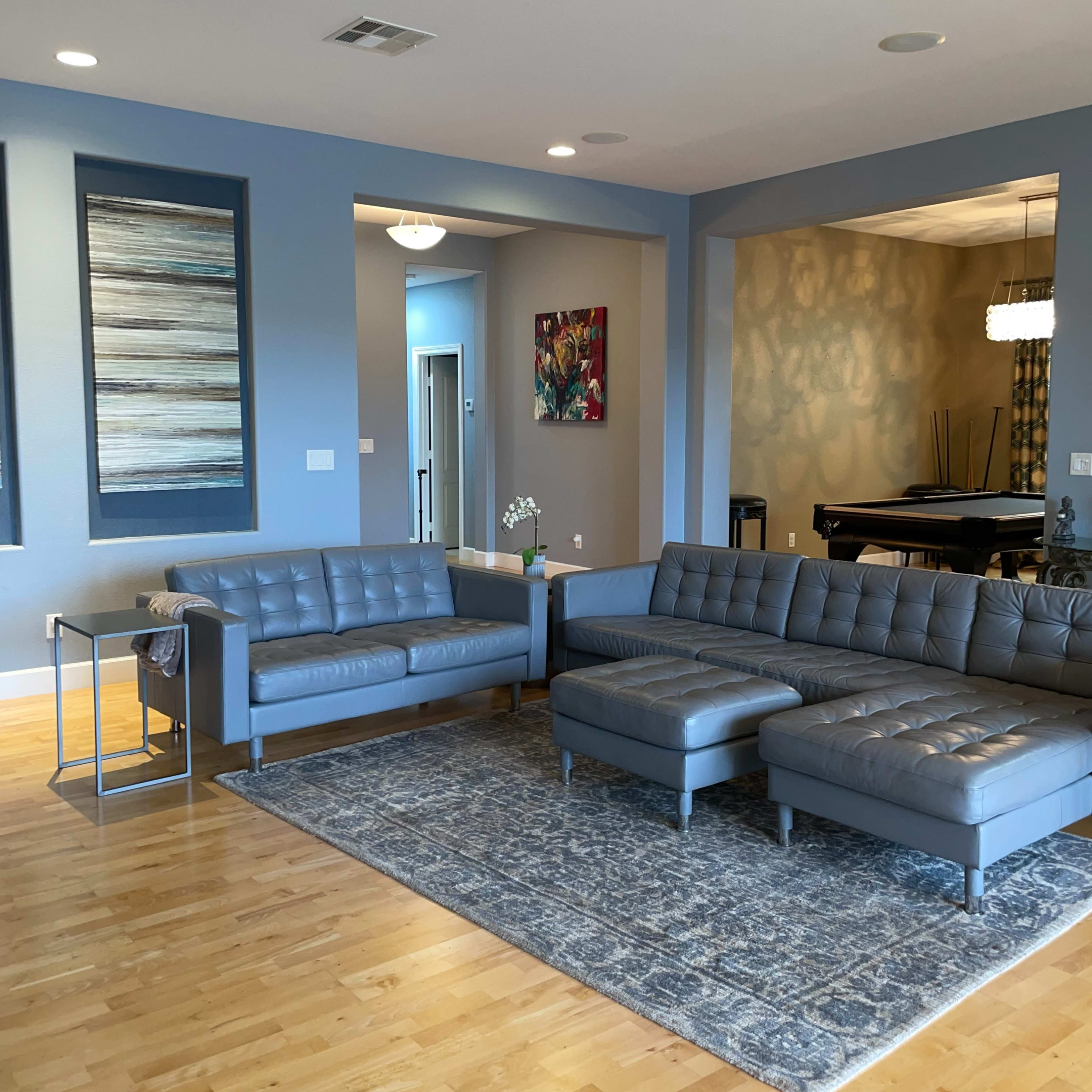 The living room features a gray sectional sofa, a matching loveseat, and a patterned area rug on light wooden flooring.