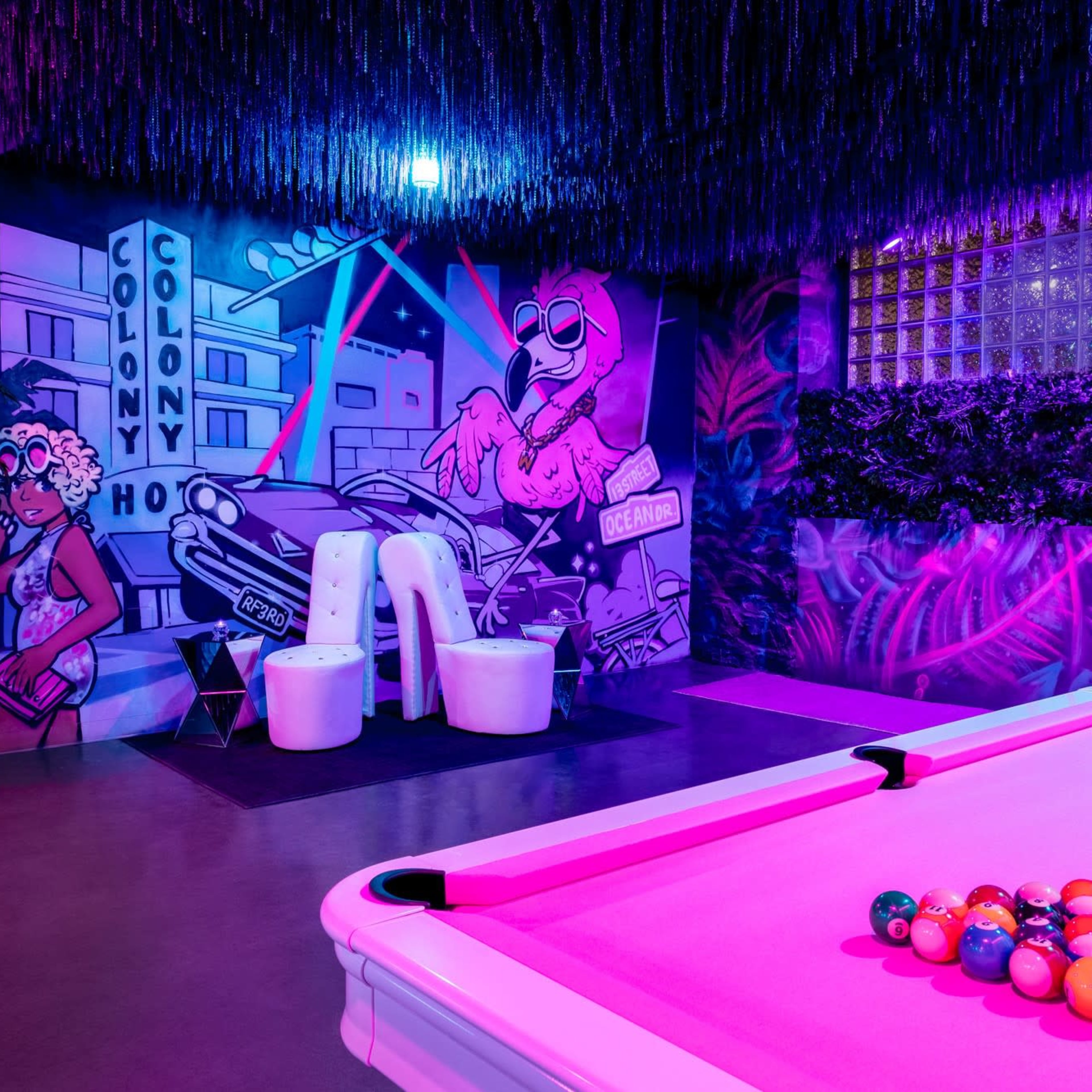 The scene features a brightly lit game area with a pool table and colorful murals on the walls, including a depiction of a car and various characters.