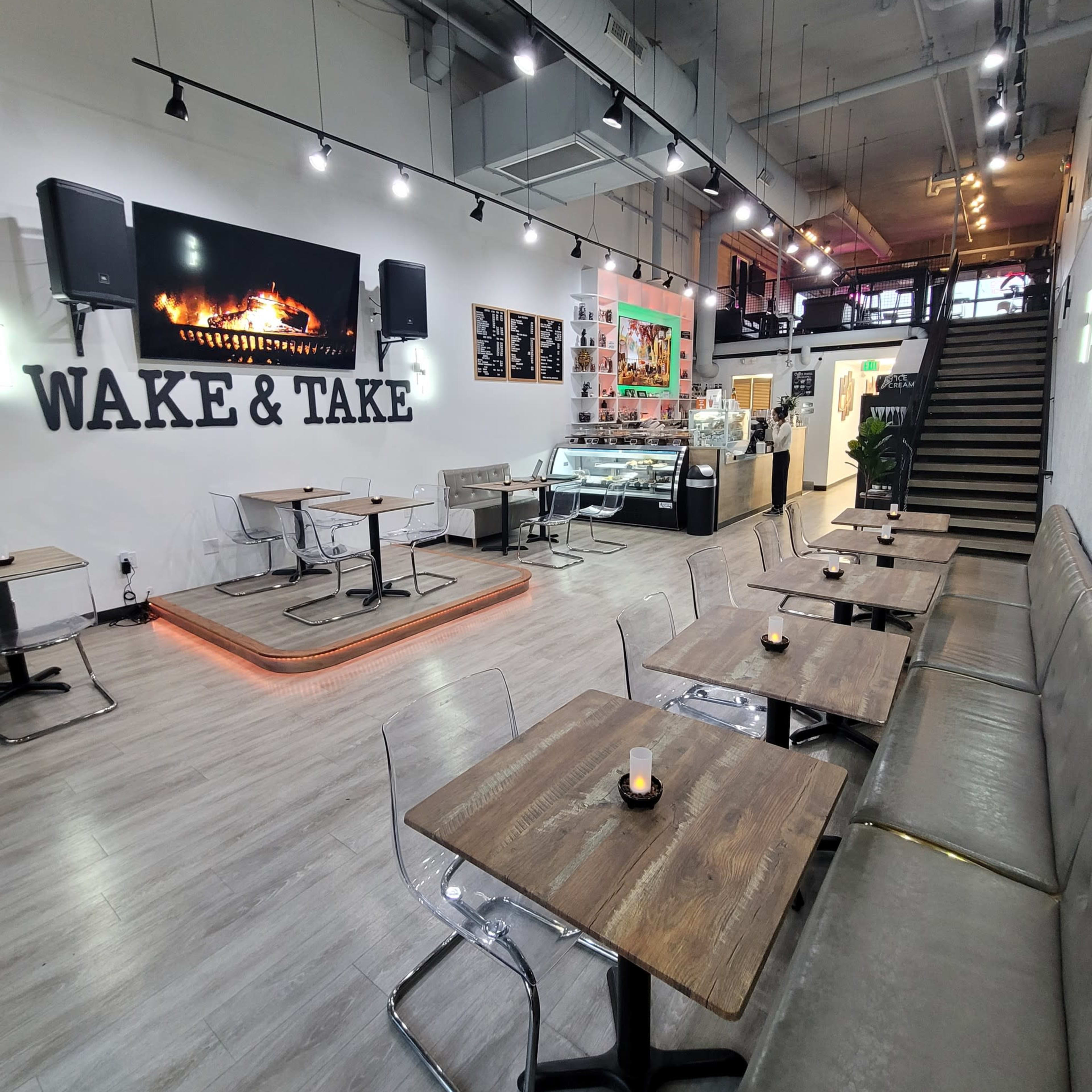 A modern café with wooden tables, clear chairs, and a counter displaying food and drinks, all set in a well-lit space.