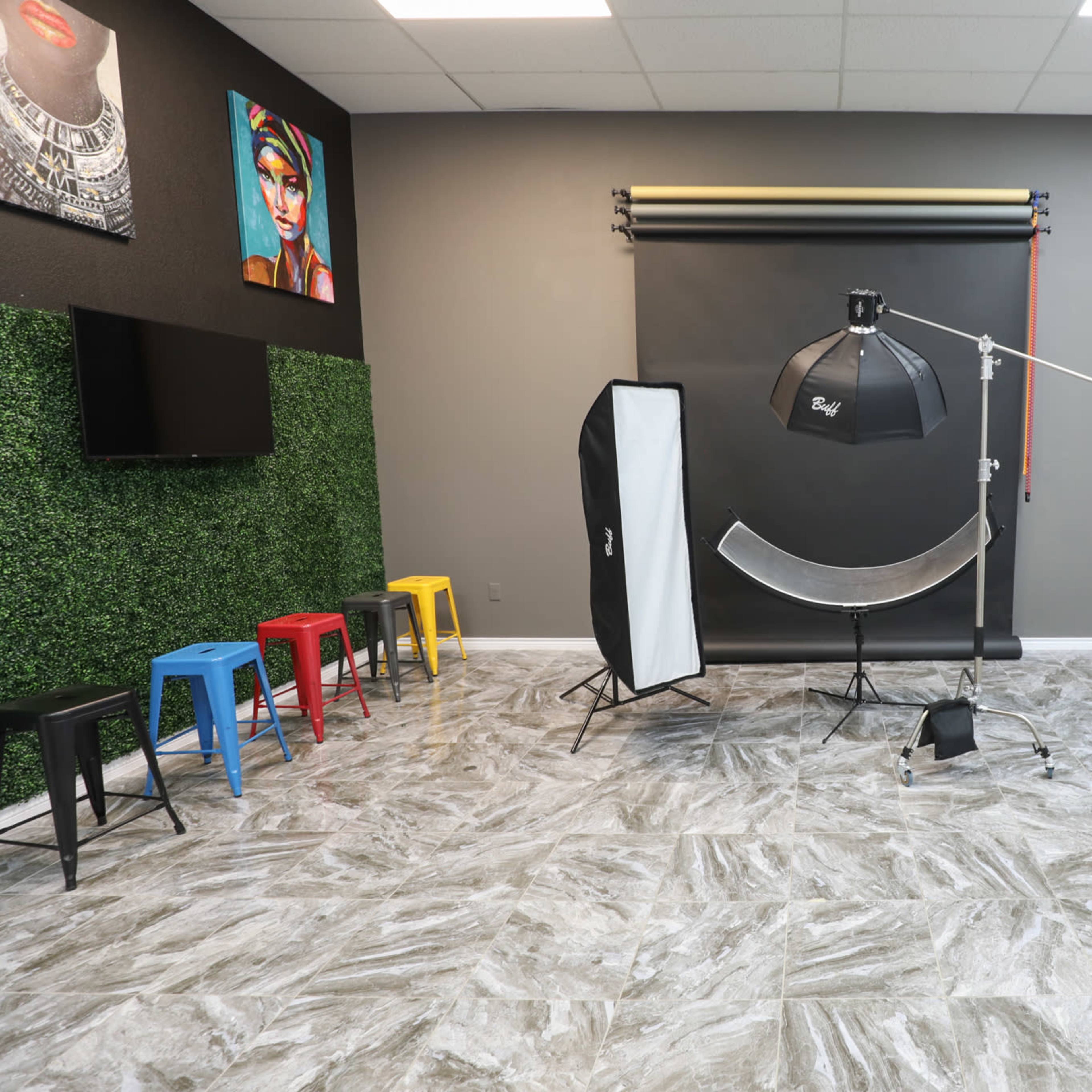A photography studio equipped with a backdrop, lighting equipment, and colorful stools arranged against a green wall.