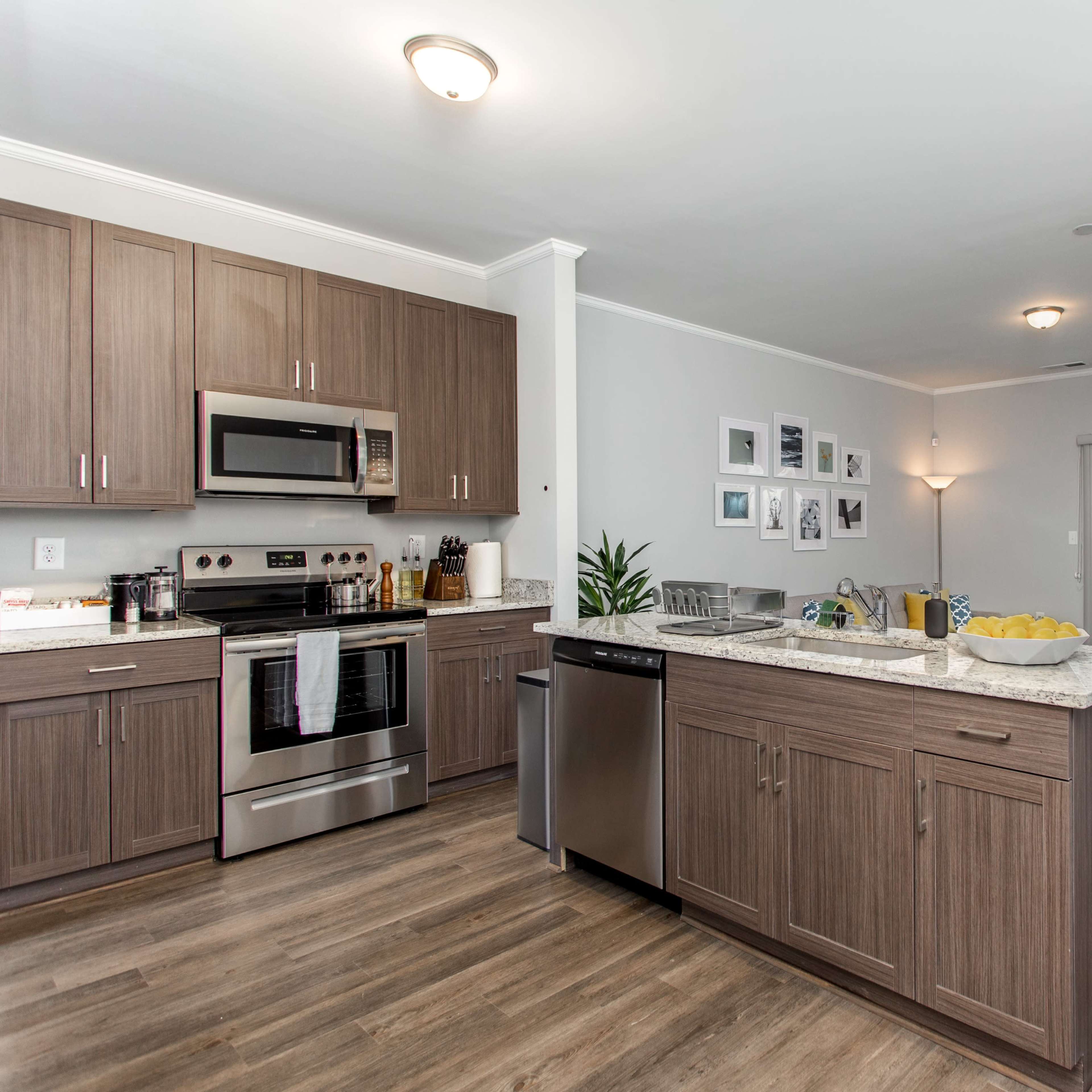 A modern kitchen with wooden cabinets, stainless steel appliances, and a dining area featuring a small table and chairs.