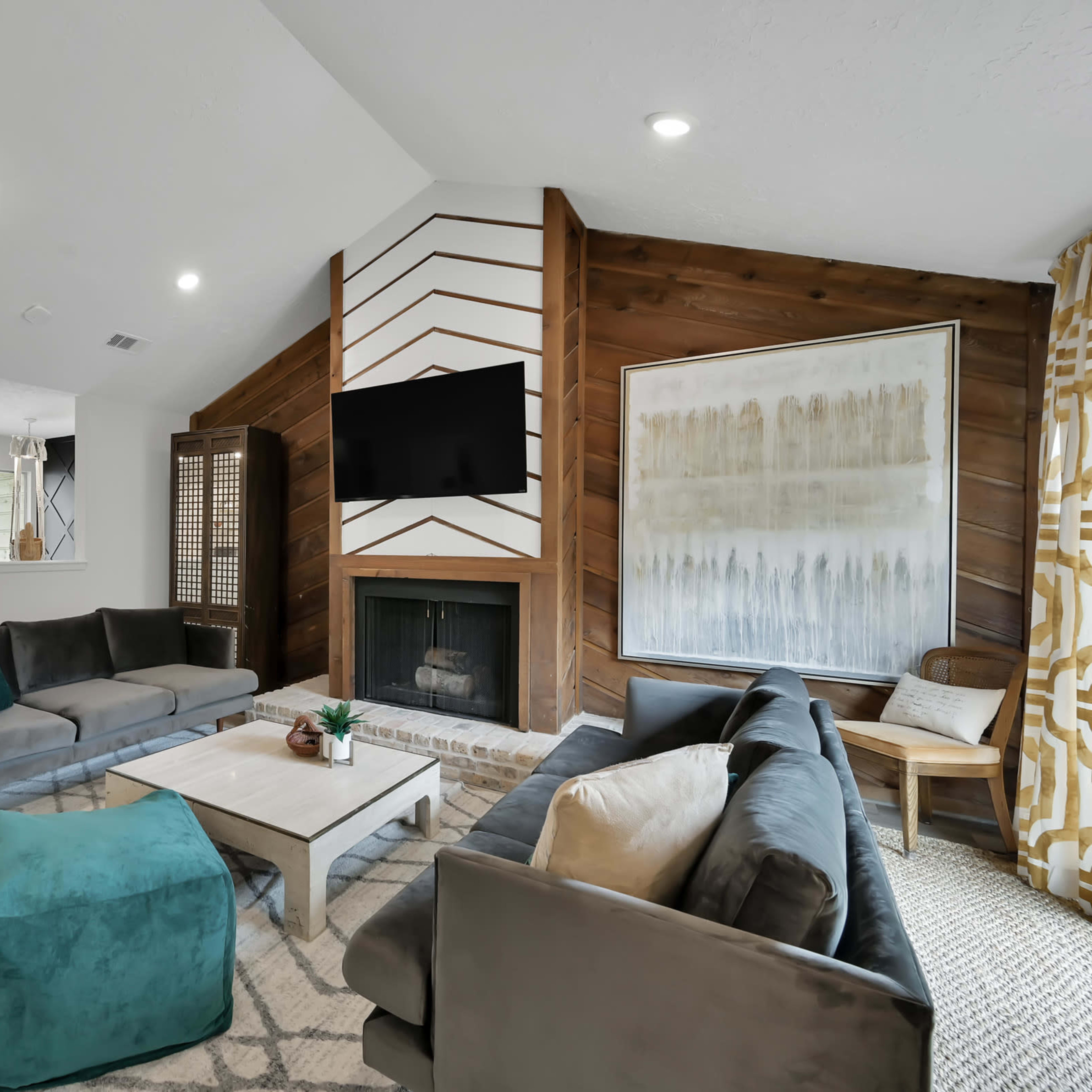 A modern living room features a fireplace complemented by a mounted television, surrounded by seating and decorative elements on a light-colored floor.