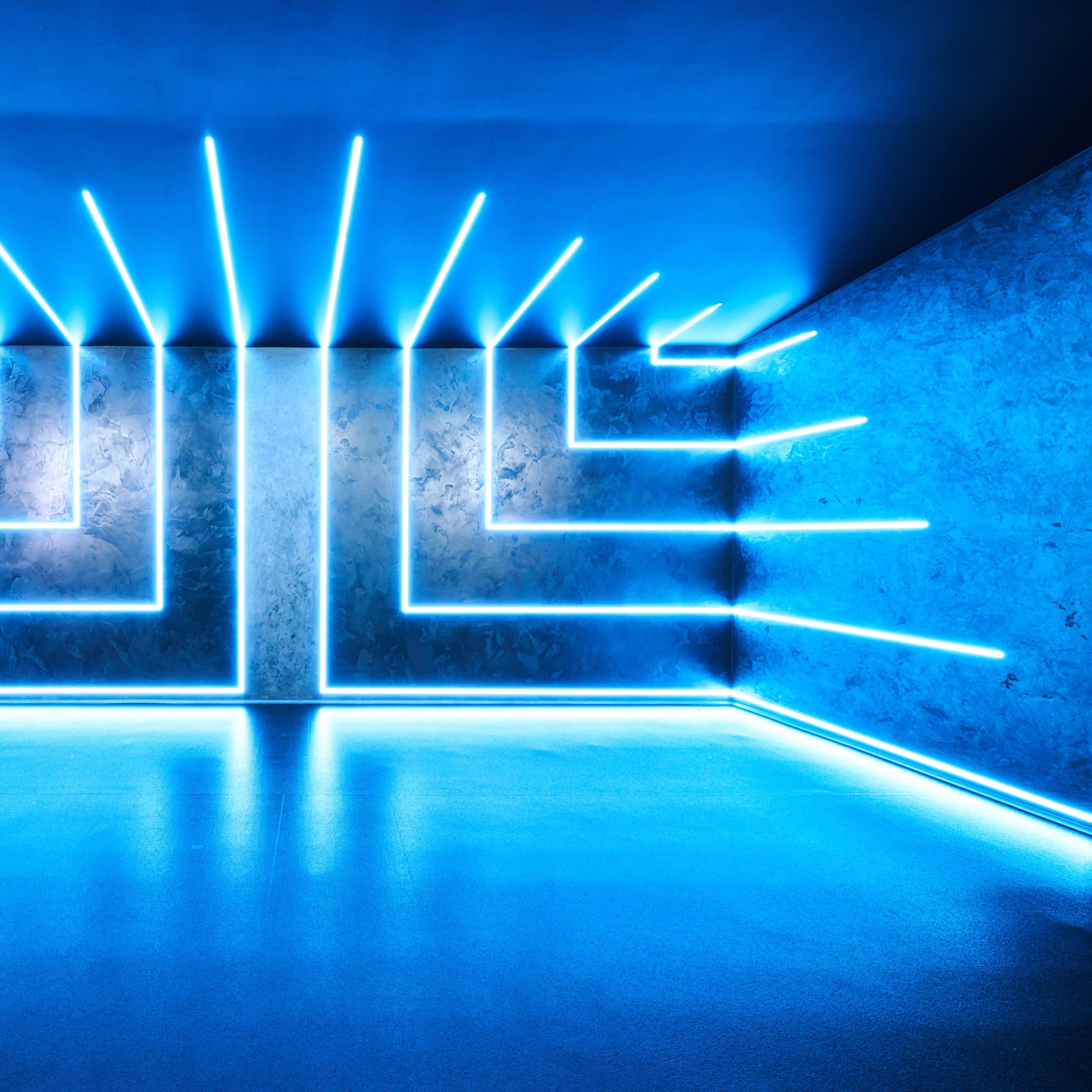 A room with blue neon lights arranged in a geometric pattern along the walls and floor.