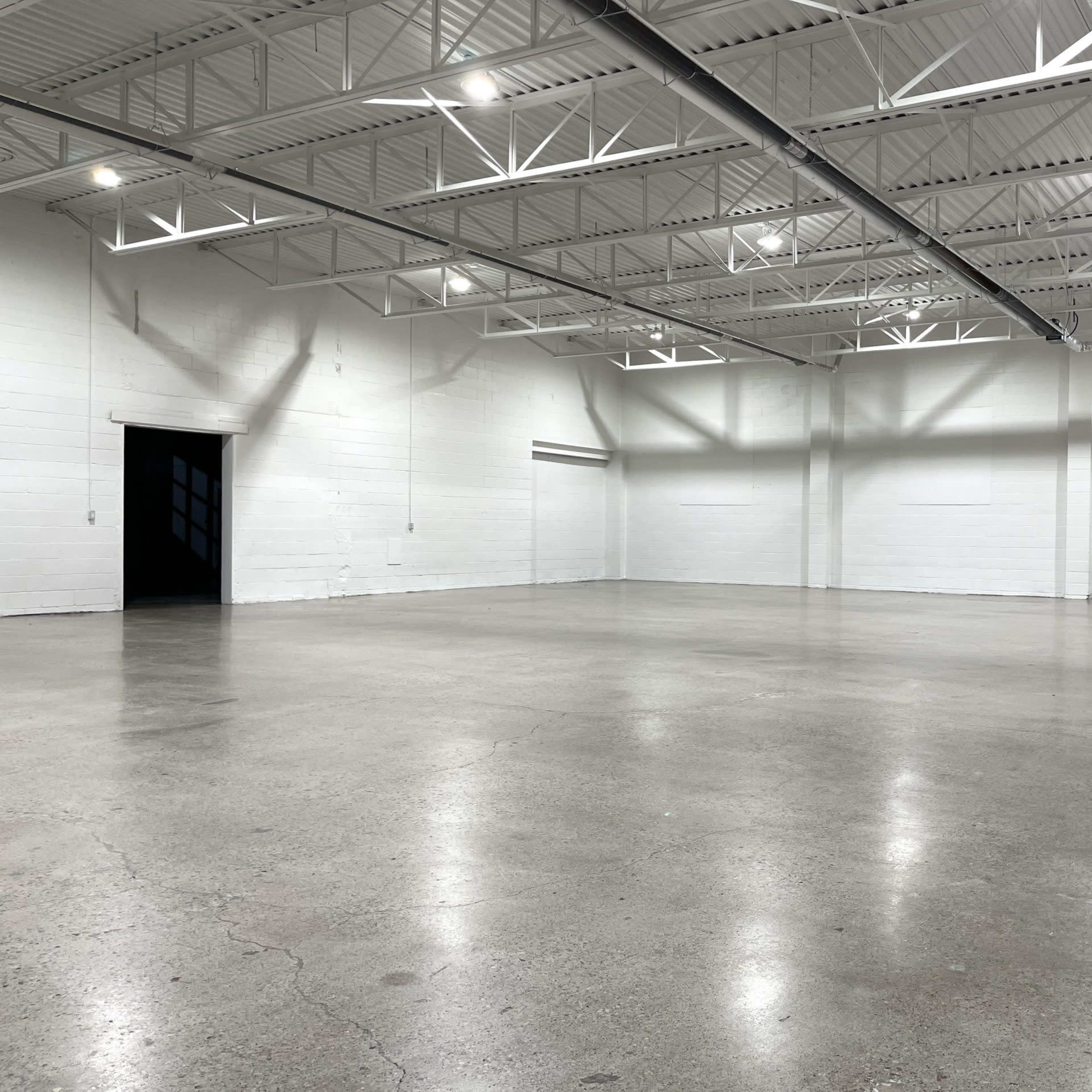 An empty warehouse space with a polished concrete floor and white walls.